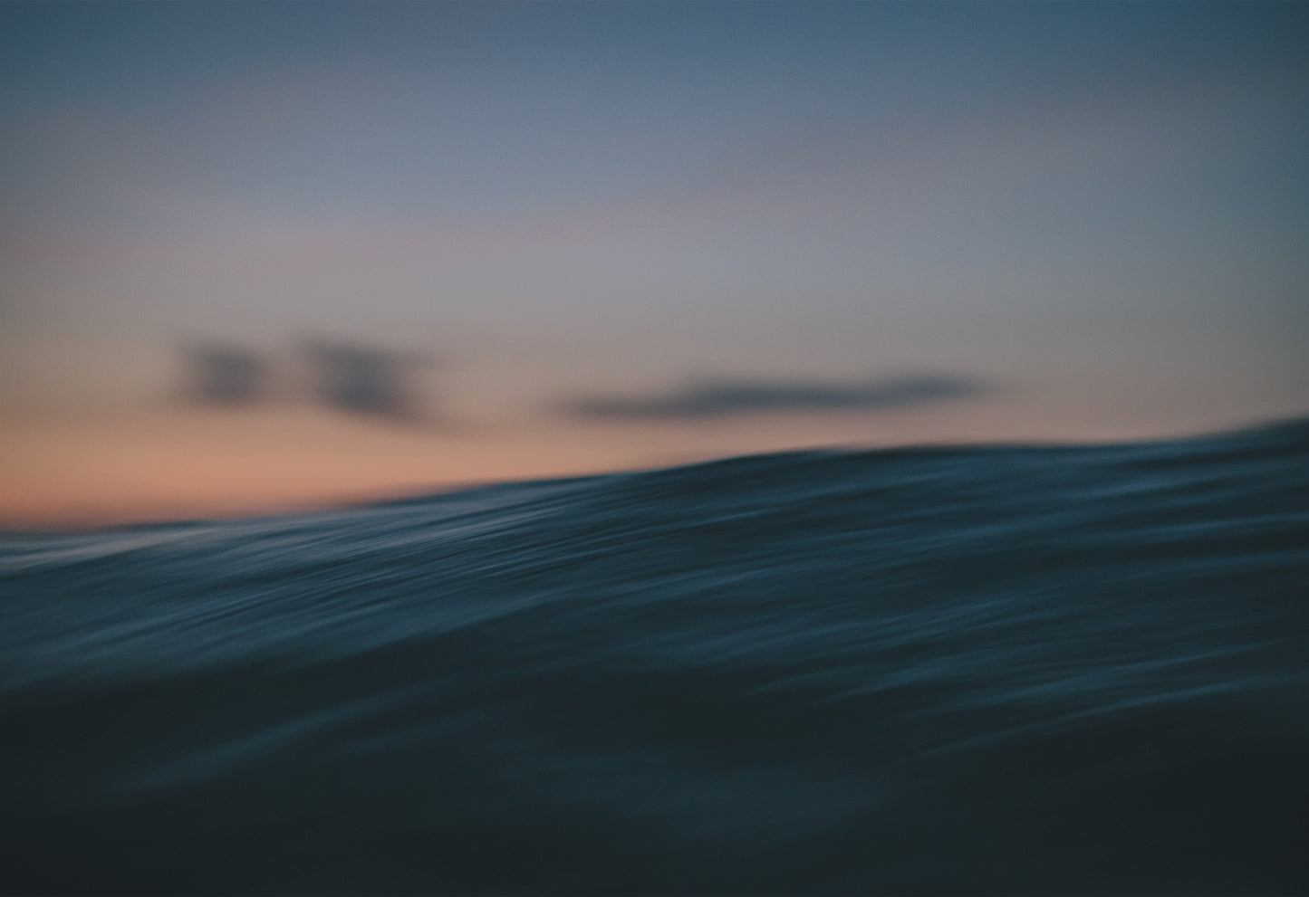 Photograph of an ocean wave at sunset taken from water level, with soft pastel skies and motion blur, part of The Sunset Journals series by Chris Hall available exclusively on The Lost Works gallery.