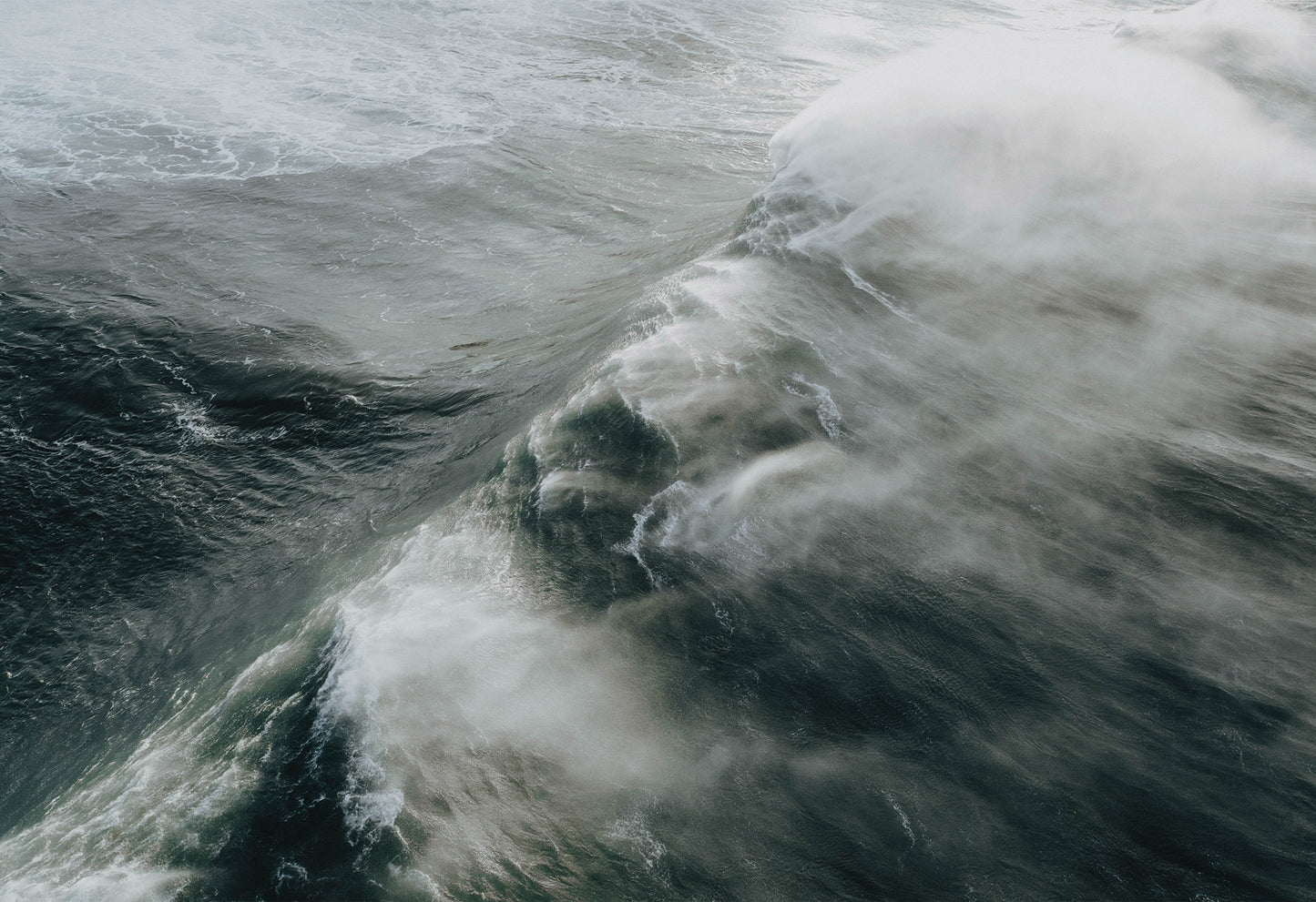 Massive 40ft wave crashing toward the shore at the legendary big wave surf spot Nazaré – a fine art travel photograph by Sam Morris.