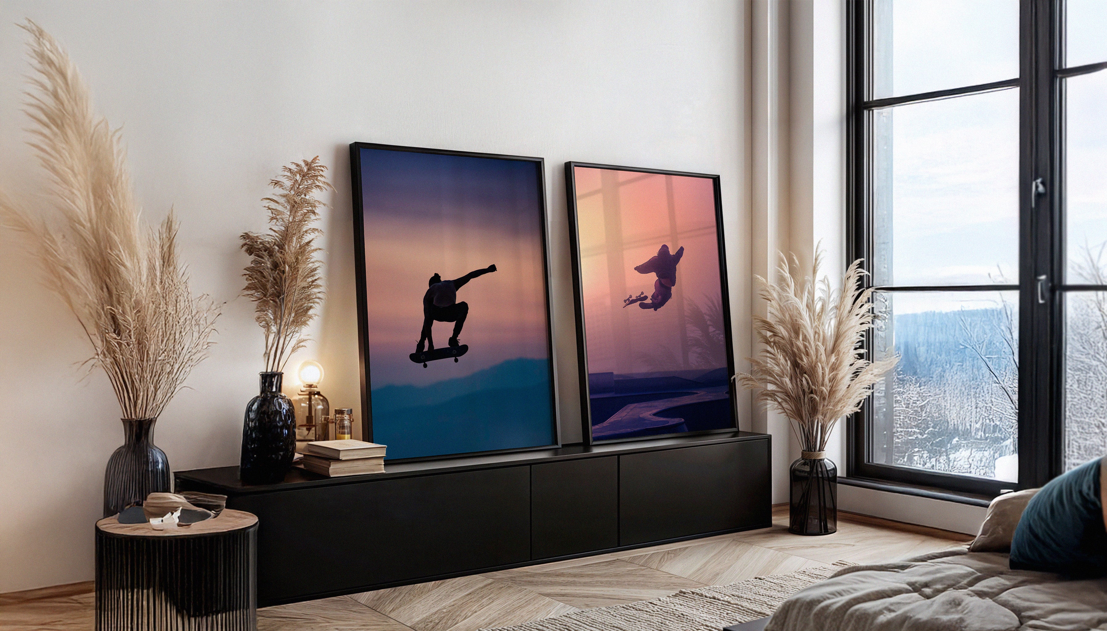 Paired skateboarding prints leaning against a living room wall: "Mountain Air" and "Above" by Craig Hubbard, next to pampas grass and large windows.