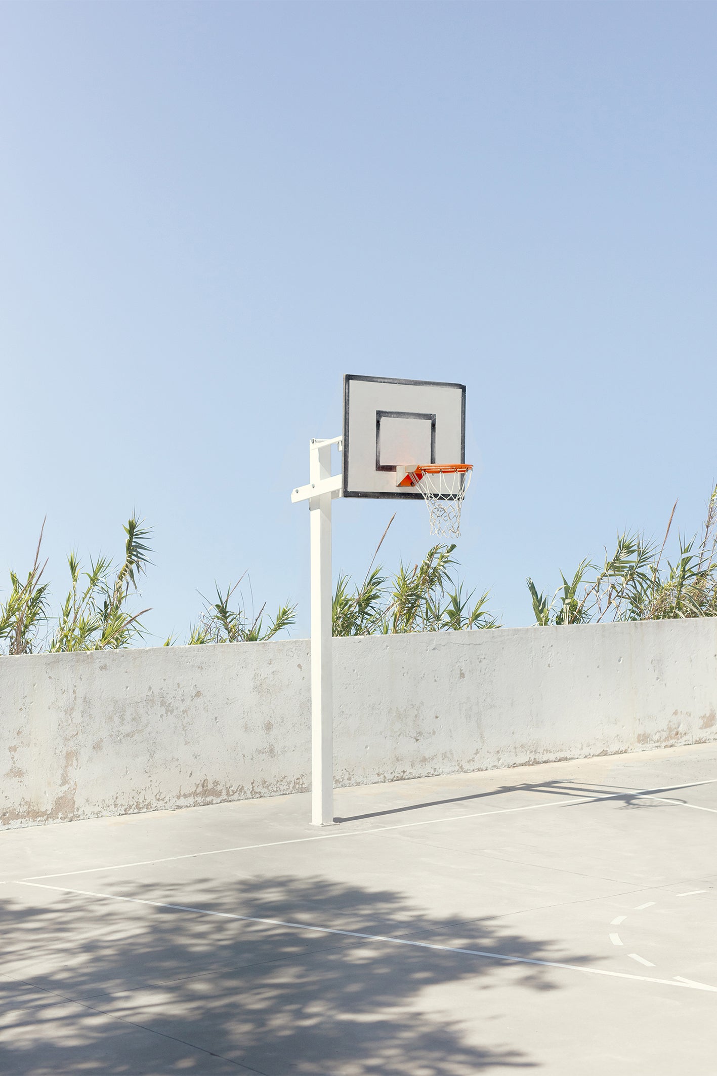 A picture-perfect basketball court captued by Will Bremridge somewhere along the Algarve coastline. Urban meets coast with the dappled shade of a tree hitting the concrete. Available to purchase from The Lost Works as a ready-to-hang framed fine art print.