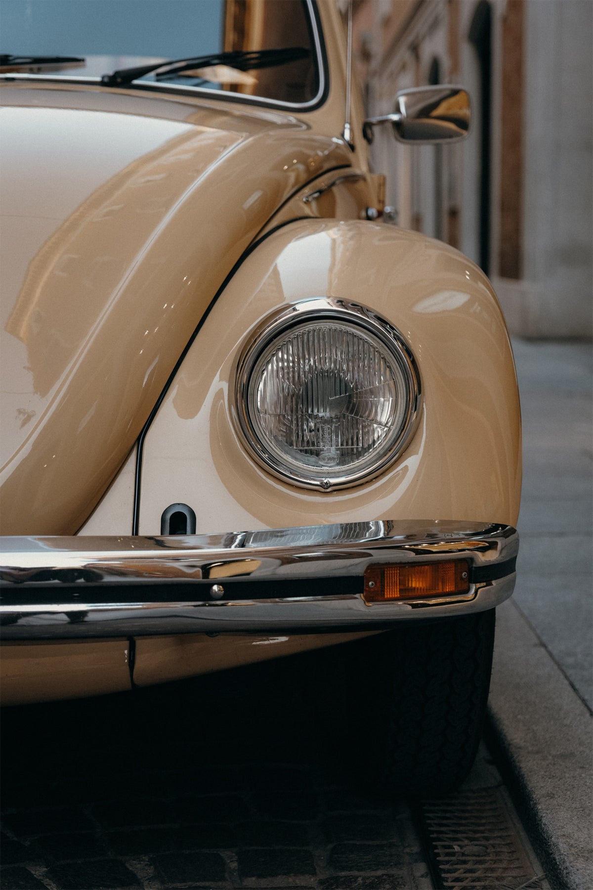 A fine art photography print of a classic VW Beetle parked up in the city centre of Modena in light beige colour, by Hannes Klager.