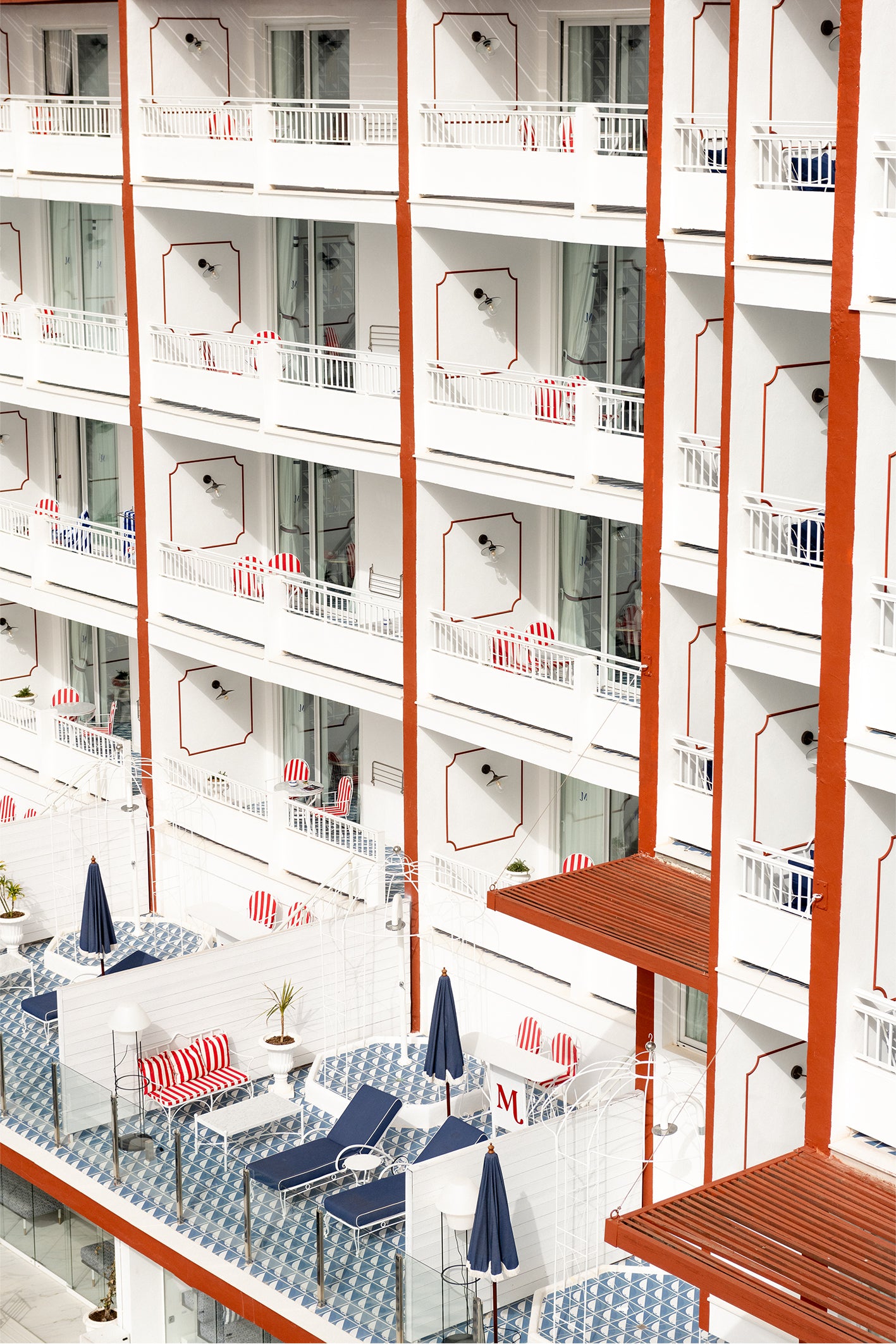 The balconies of a hotel in Ibiza, with playful geometric patterns in red, white and blue - a fine art photography print by Evie Johnstone.