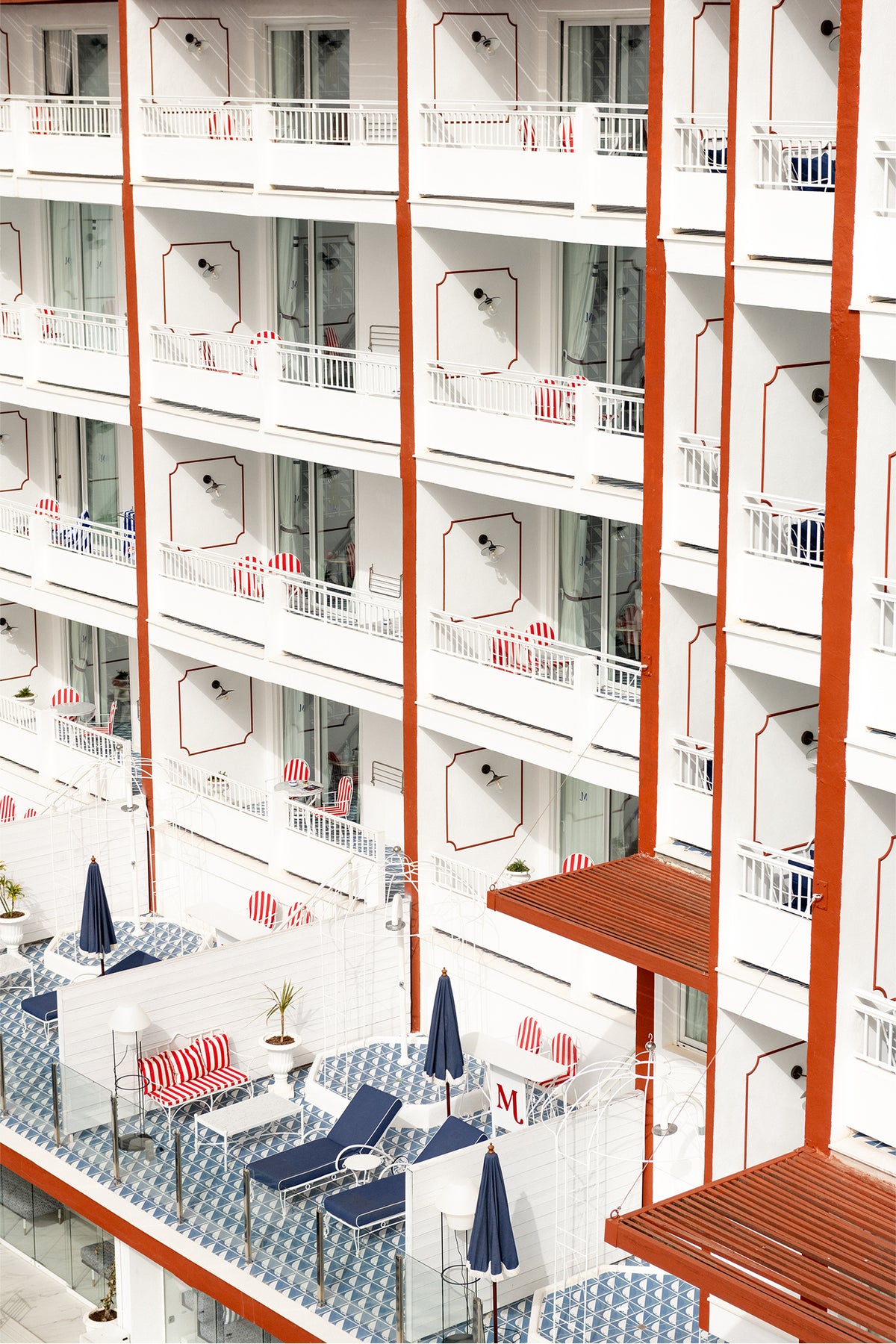 The balconies of a hotel in Ibiza, with playful geometric patterns in red, white and blue - a fine art photography print by Evie Johnstone.