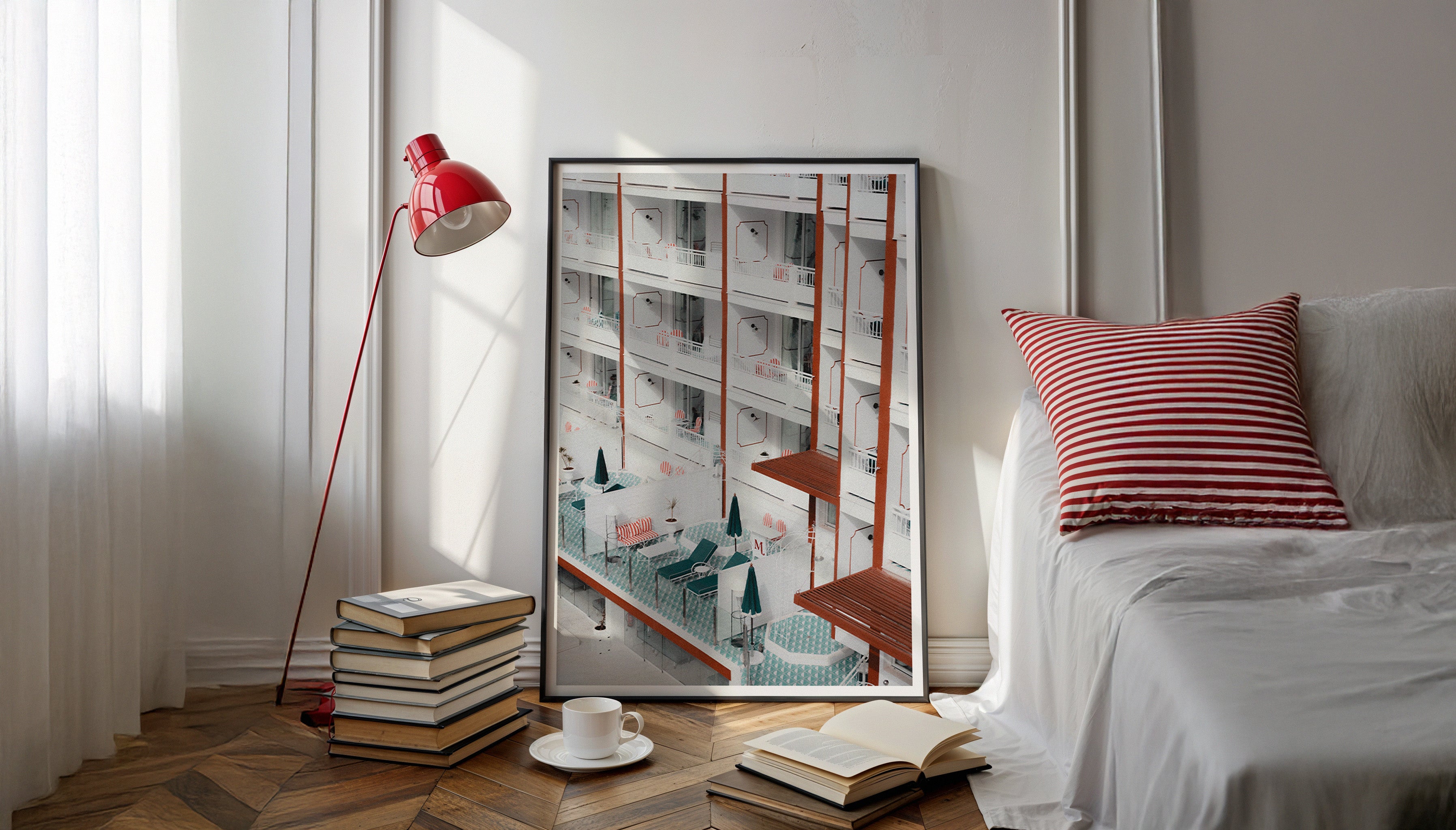 Wide view of a white bedroom with red accents like a red lamp and a red and white striped pillow, showcasing Evie Johnstone's ready-to-hang photography print BALCONIES in a large black frame leaning against the wall.