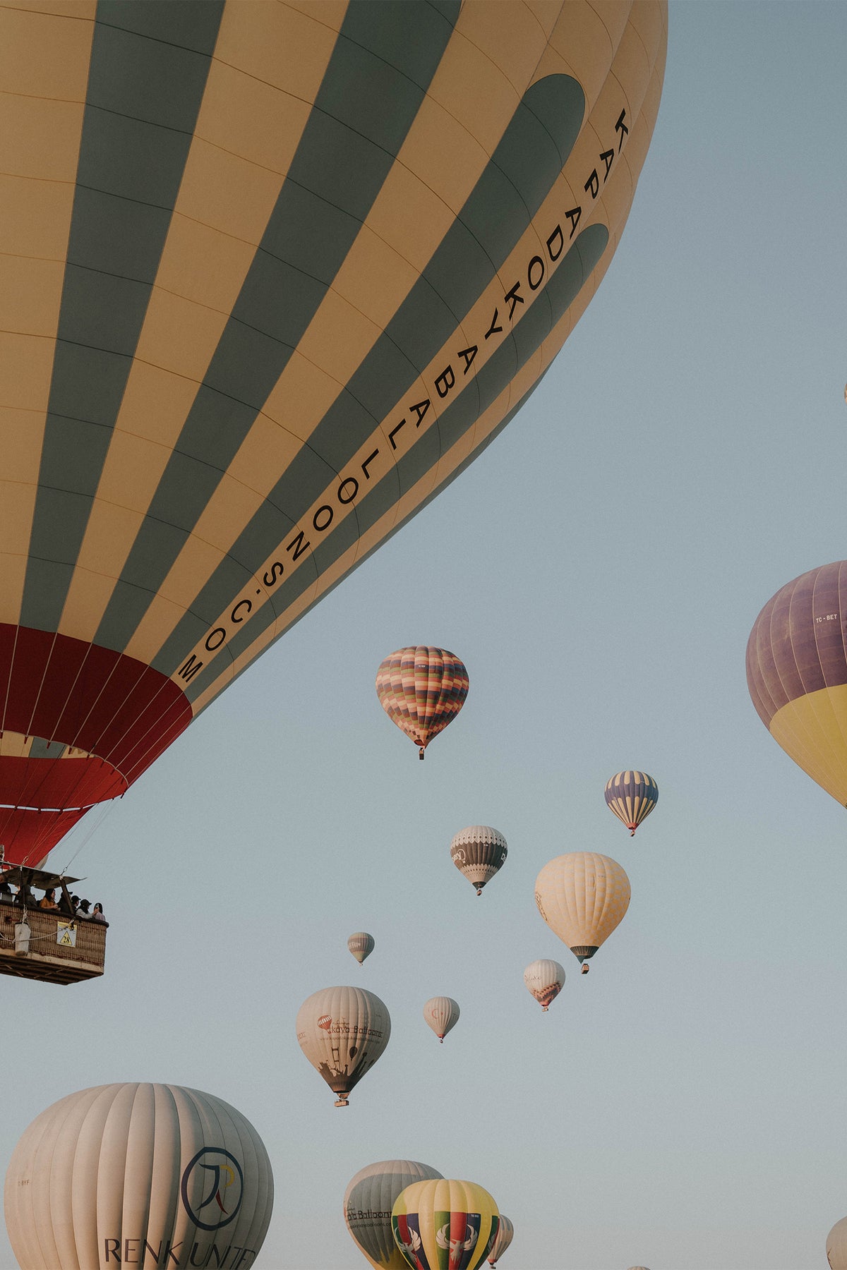 Flying above the landscape of Cappadocia, hundreds of hot air balloons drift across the sky. A serene fine art print by photographer Sam Morris.