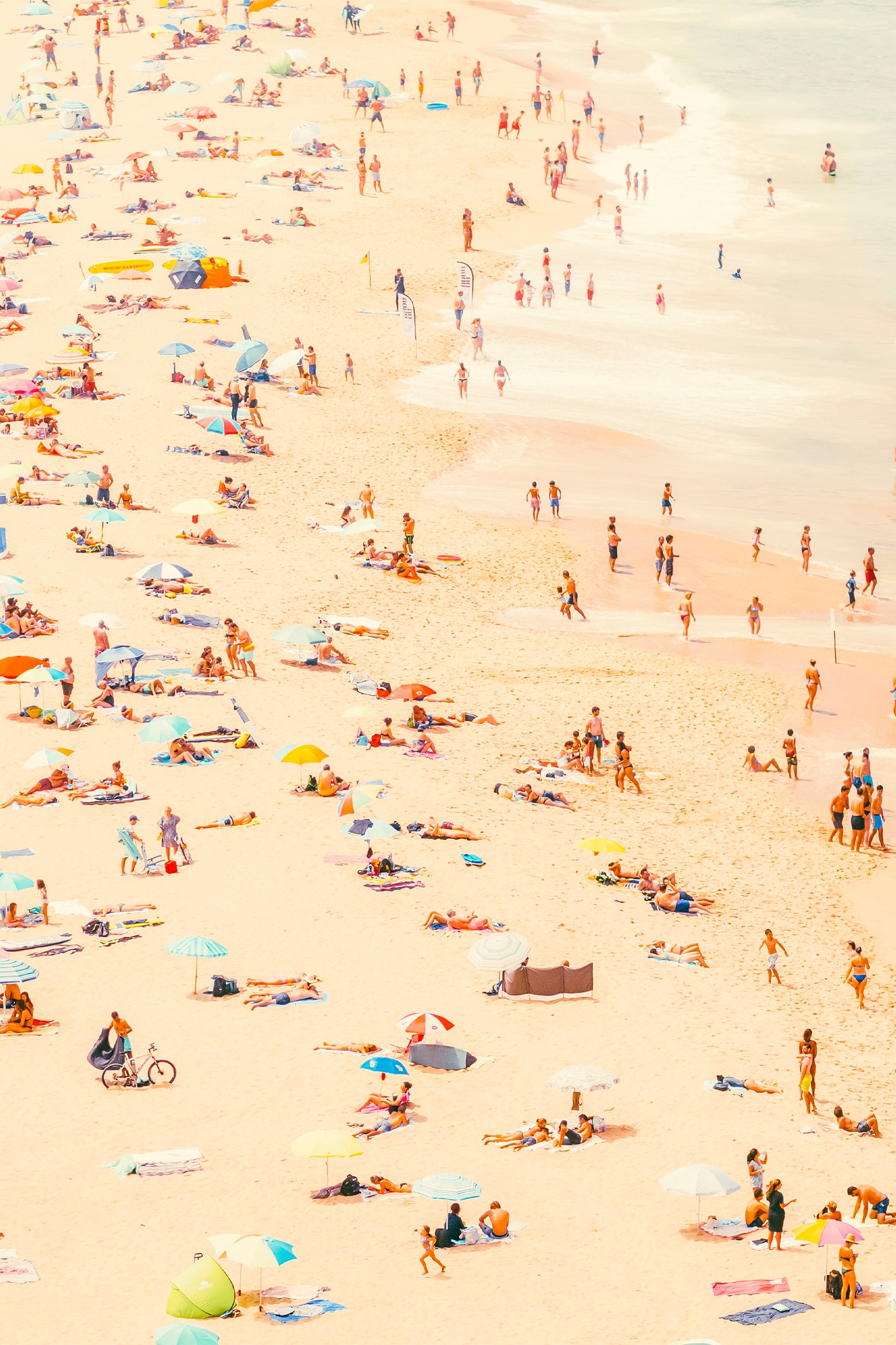 A busy summer's day In Ericera. Get lost in a typical beach scene, with sun bathers, parasols, surf boards and water frolicking. A fine art photography print by Will Bremridge, available to purchase on The Lost Works.