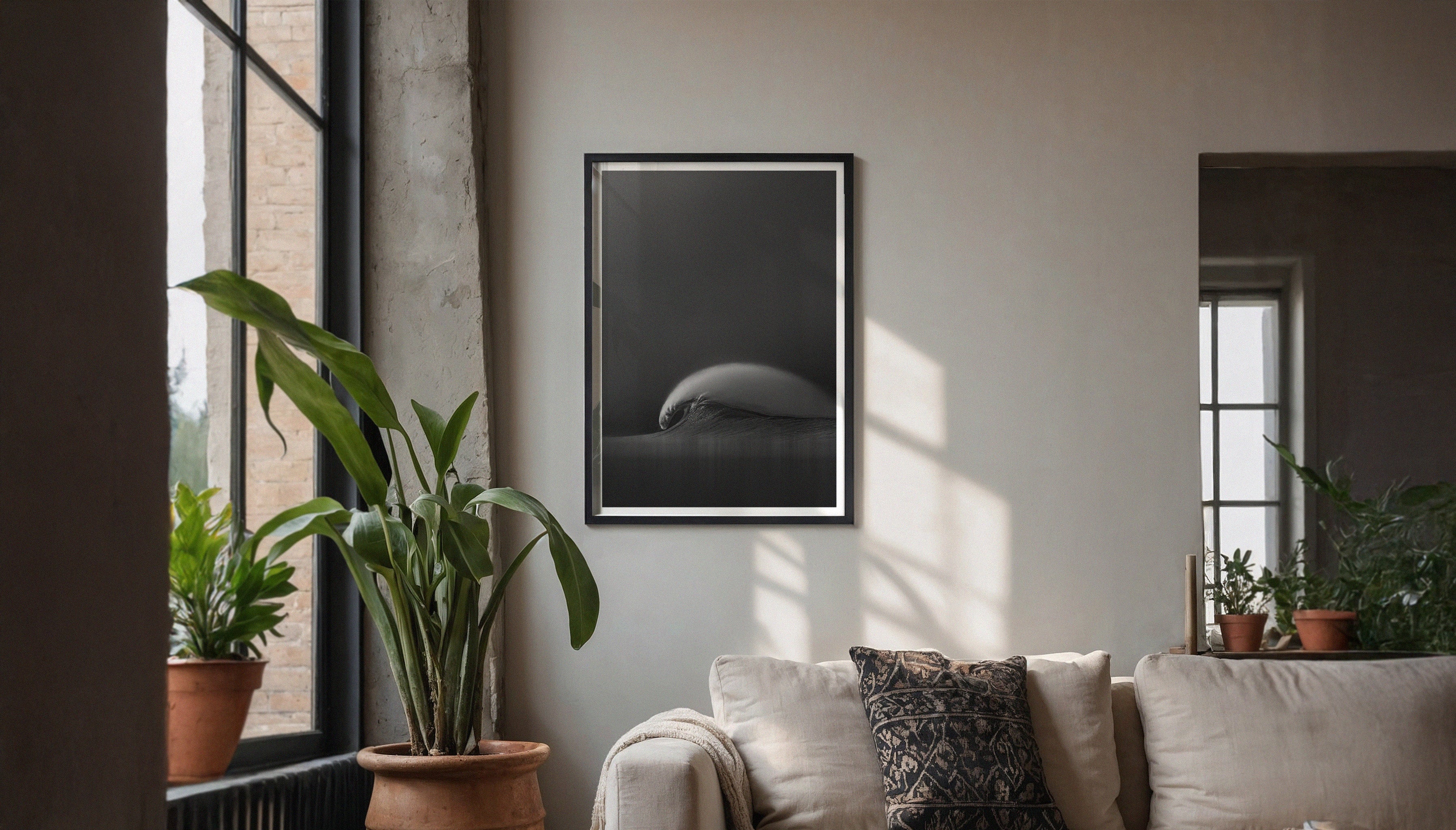 “Capsule” by Craig Hubbard, a monochrome wave photo, elegantly framed and showcased in a natural light-filled living space with indoor plants and neutral tones.