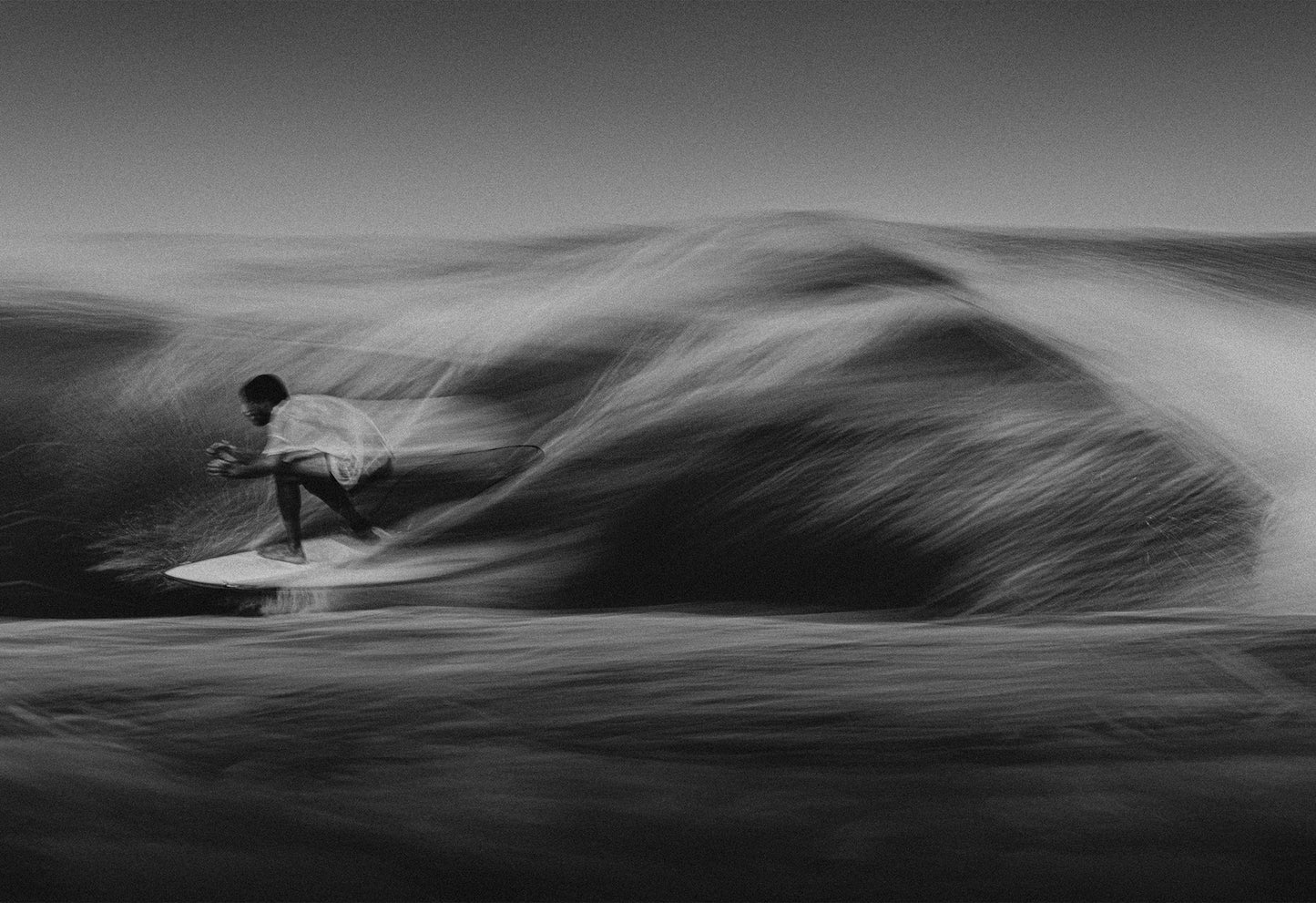Black and white motion-blurred photograph of a surfer crouching on a wave in Santa Teresa, Costa Rica, captured by Ez Rivero.