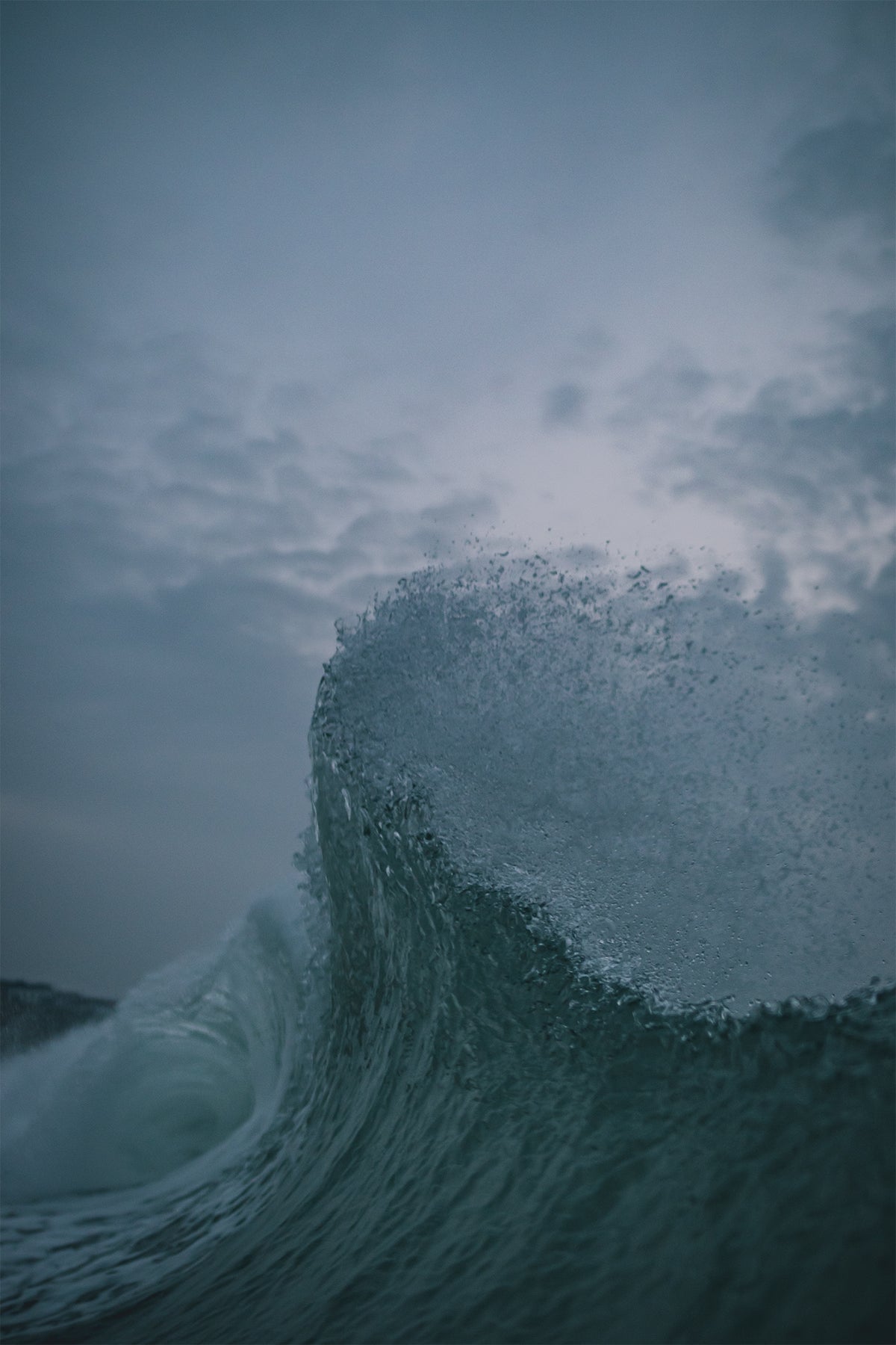 Close-up of a cresting wave captured in sharp detail under a moody evening sky by Chris Hall in Newquay, Cornwall.