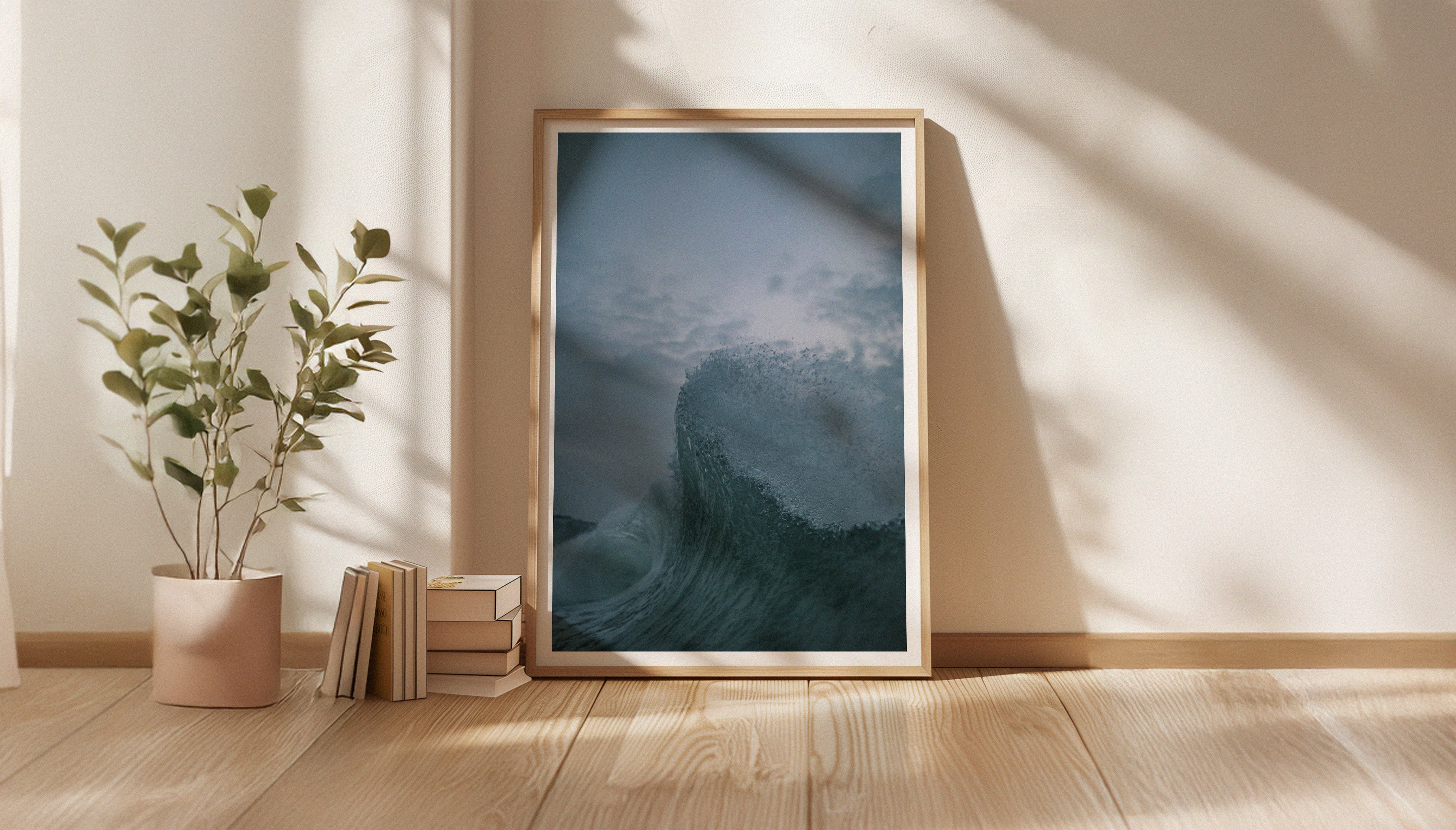 A fine art print by Chris Hall in a wooden frame, depicting a close-up of a cresting wave captured in sharp detail under a moody evening sky in Newquay, Cornwall, pictured in a Scandi-style living space.