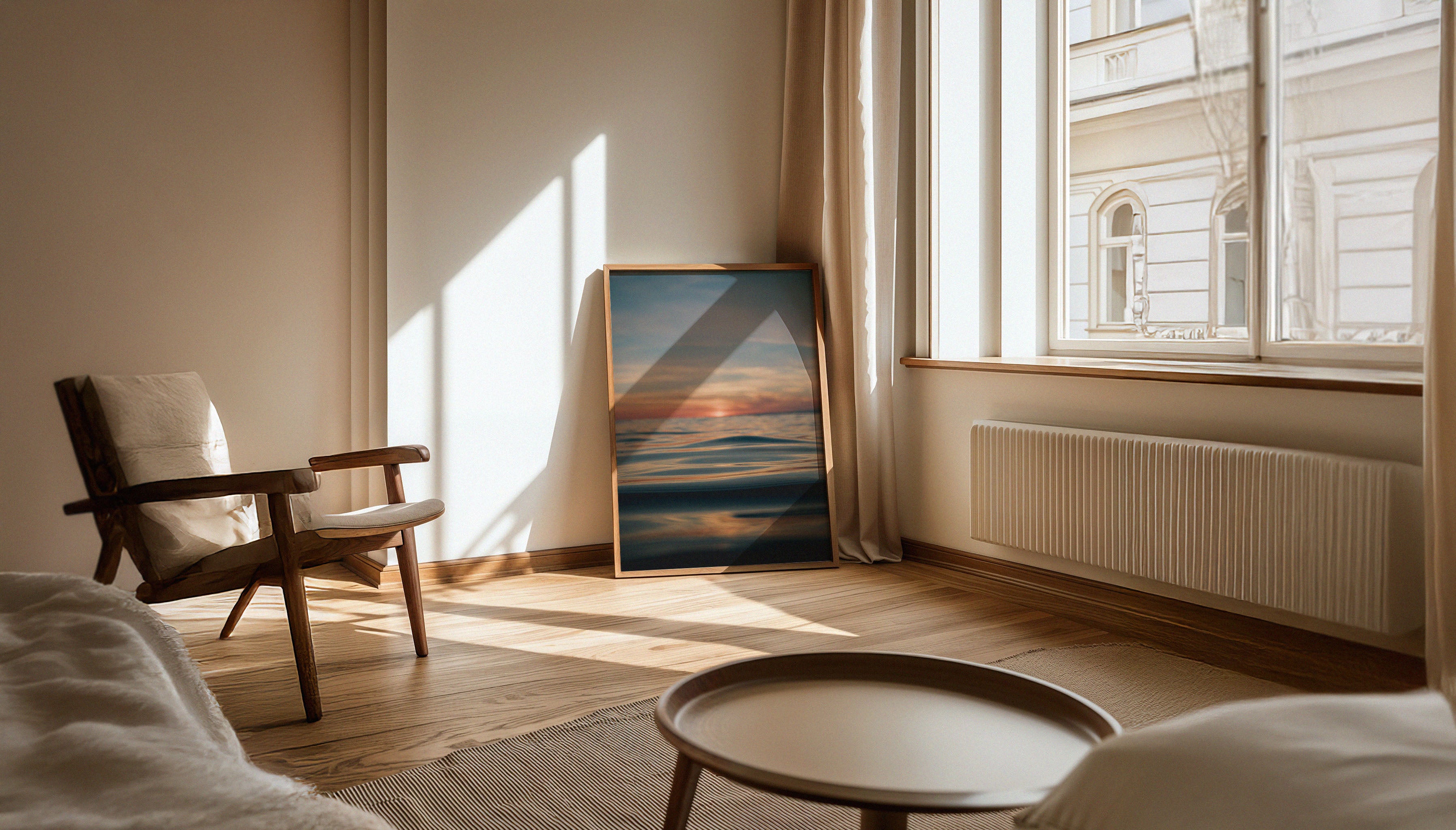 Chris Halls' fine art print depicting a sunset over a calm ocean with golden light reflecting on smooth water, taken in Newquay, Cornwall, shown in a large wooden frame leaning against a muted room wall.