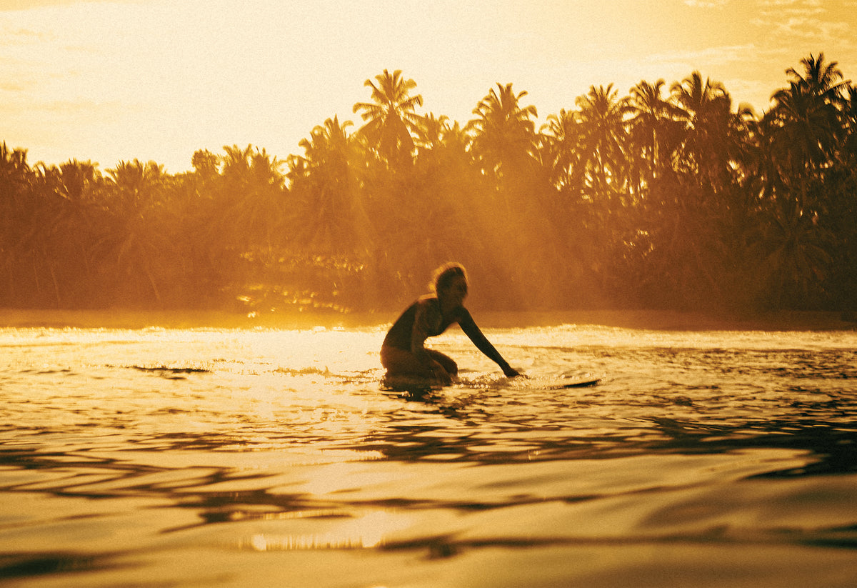 Surfer in silhouette paddling at sunset in Santa Teresa, Costa Rica, captured in golden light by Ez Rivero. Fine art travel photography print.