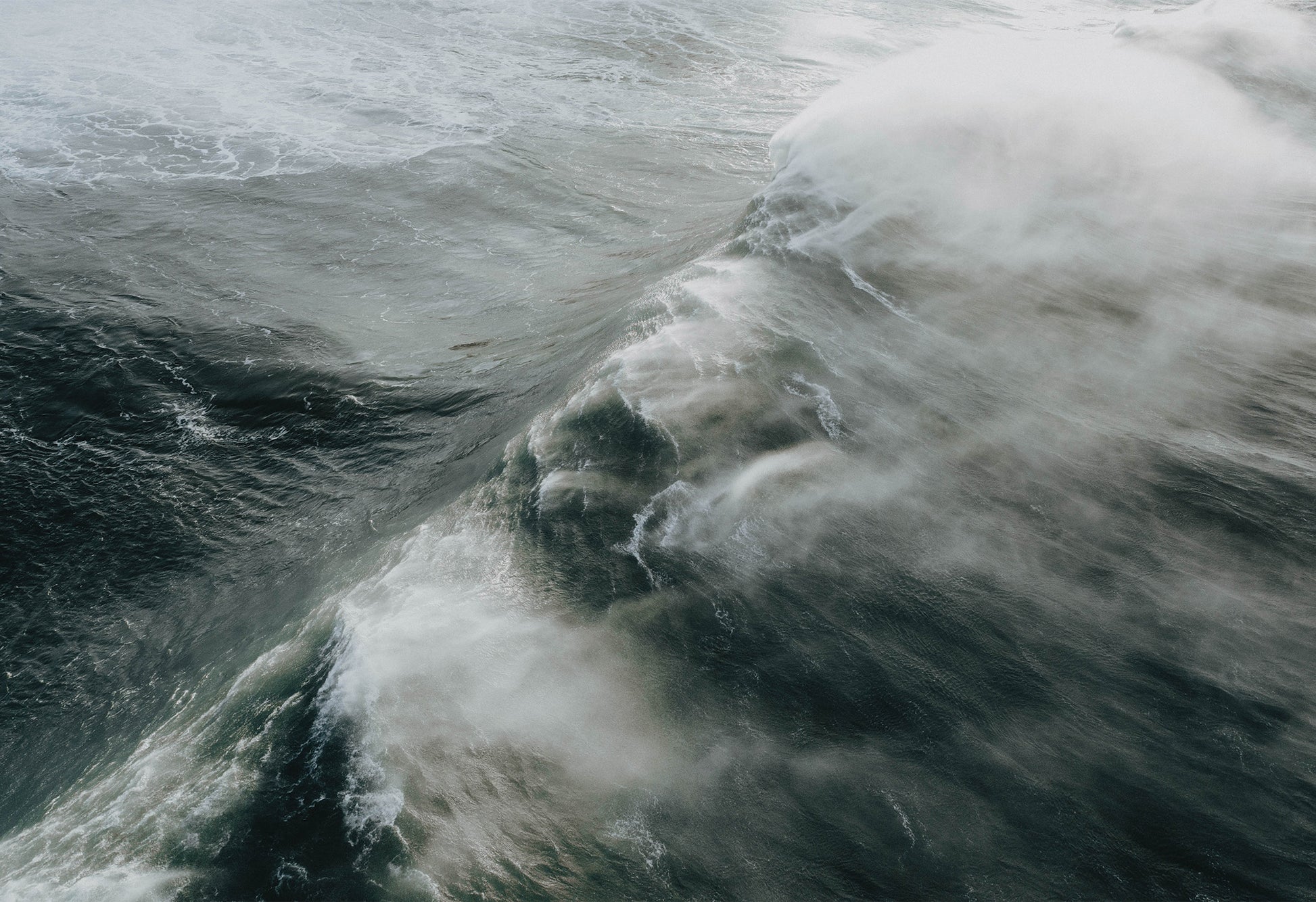 Massive 40ft wave crashing toward the shore at the legendary big wave surf spot Nazaré – a fine art travel photograph by Sam Morris.