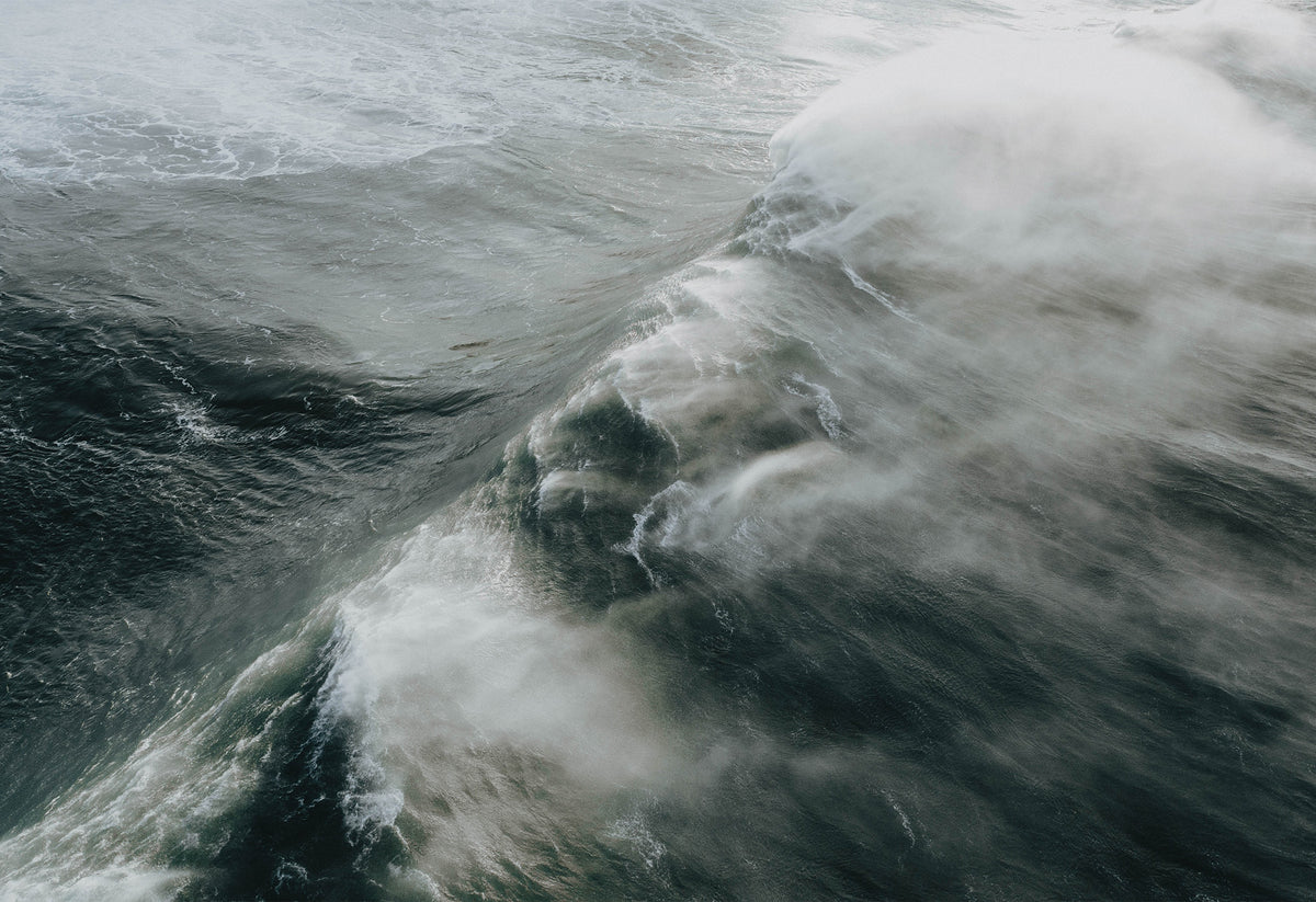 Massive 40ft wave crashing toward the shore at the legendary big wave surf spot Nazaré – a fine art travel photograph by Sam Morris.
