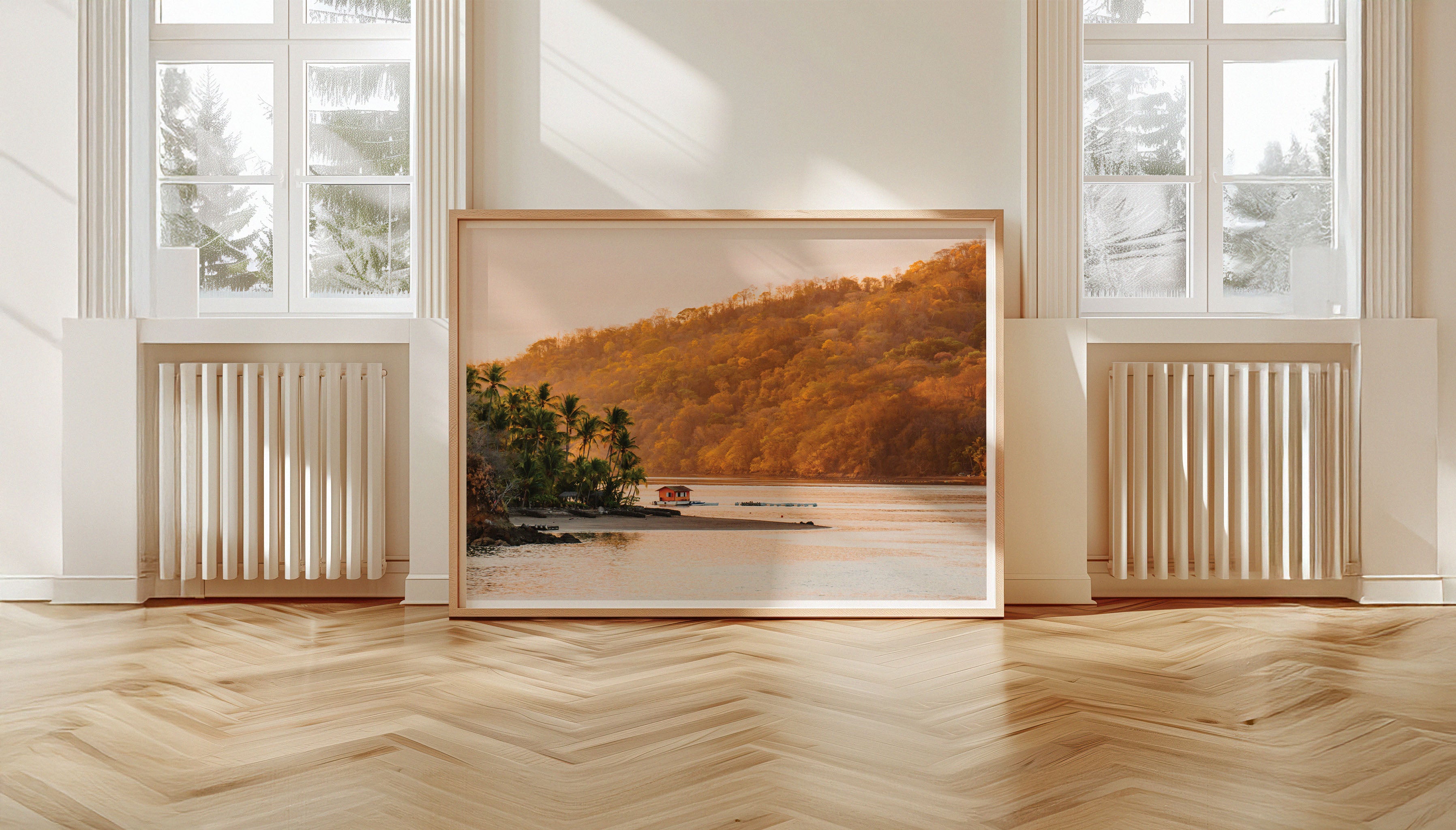 A wide angle view of Evie Johnstone's HOUSE BOAT photography wall art print, in a large wooden frame leaning against a wall next to two large windows.