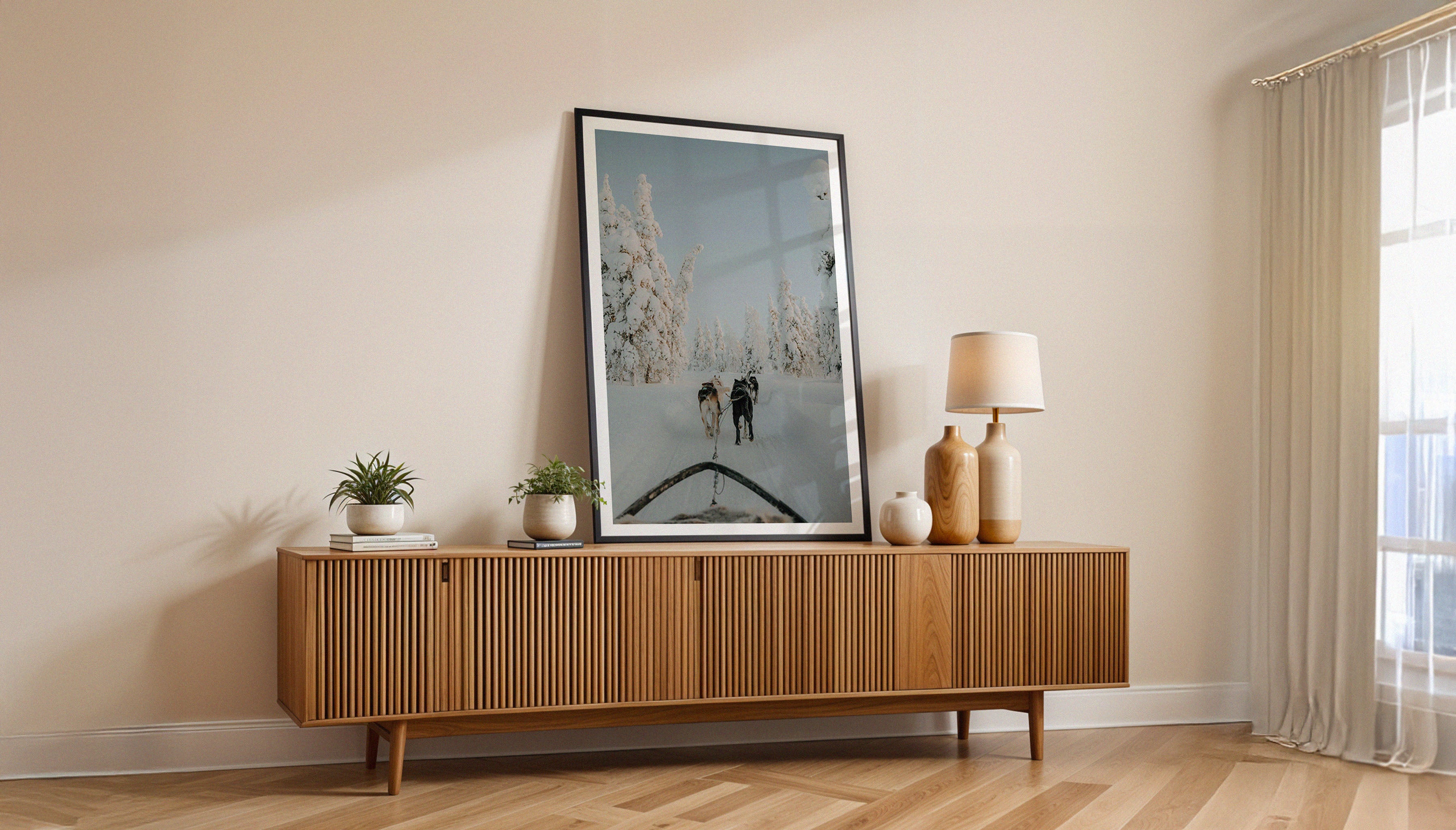 Sam Morris' fine art print depicting huskies pulling a sled through a snow-covered Finland landscape, with trees heavy with snow in sub-zero temperatures, shown in a black frame in a hallway.