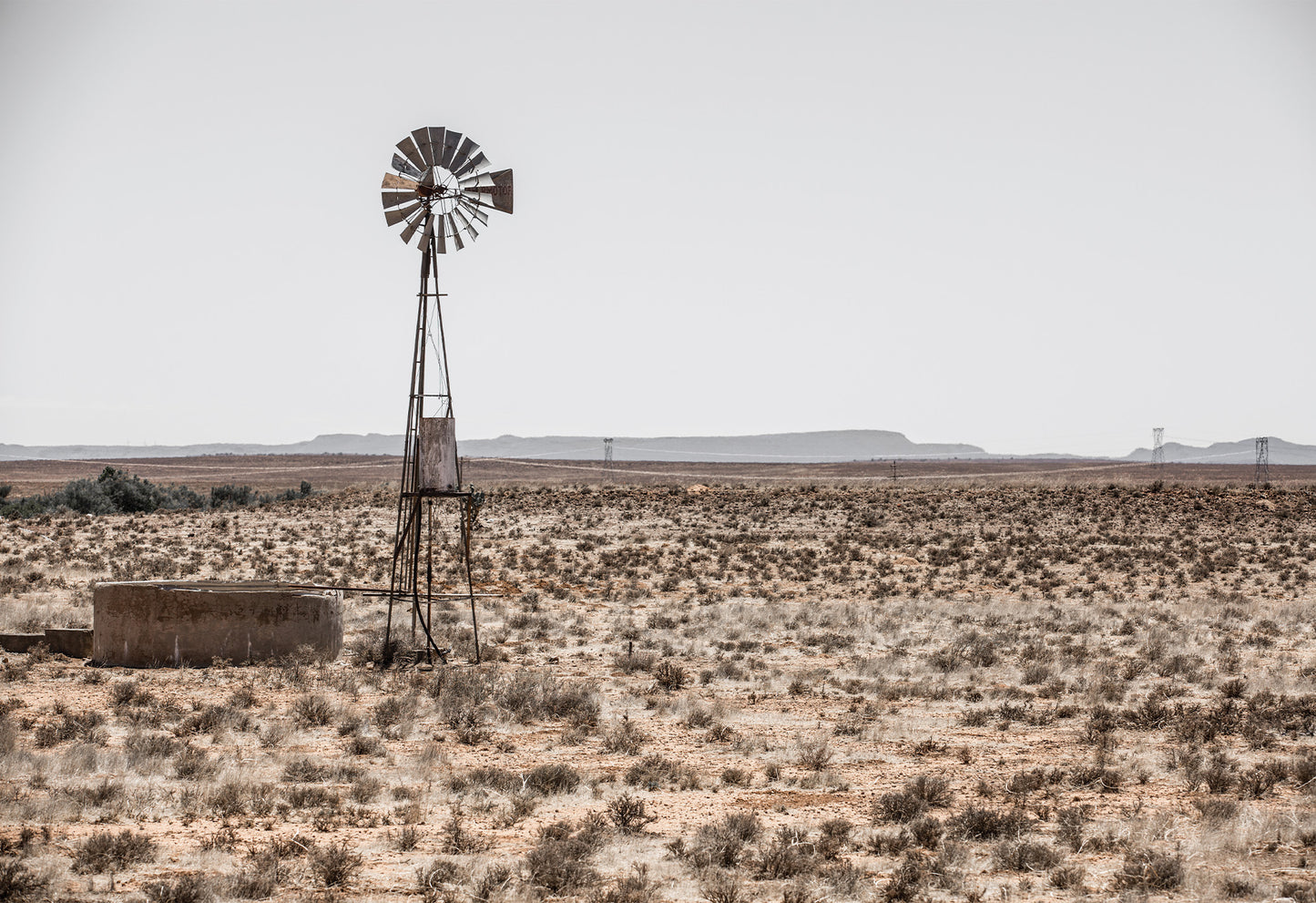 A typical farm scene in the Karoo showing a 'windpomp' or windpump in an arid African landscape - fine art print by Charles Johnstone.