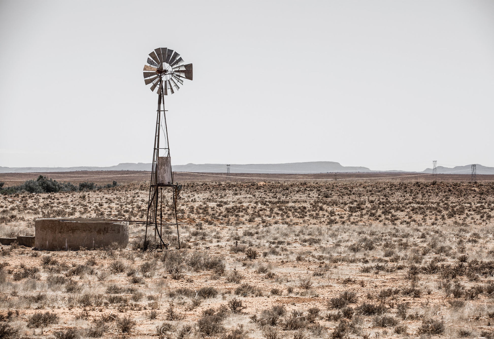 A typical farm scene in the Karoo showing a 'windpomp' or windpump in an arid African landscape - fine art print by Charles Johnstone.