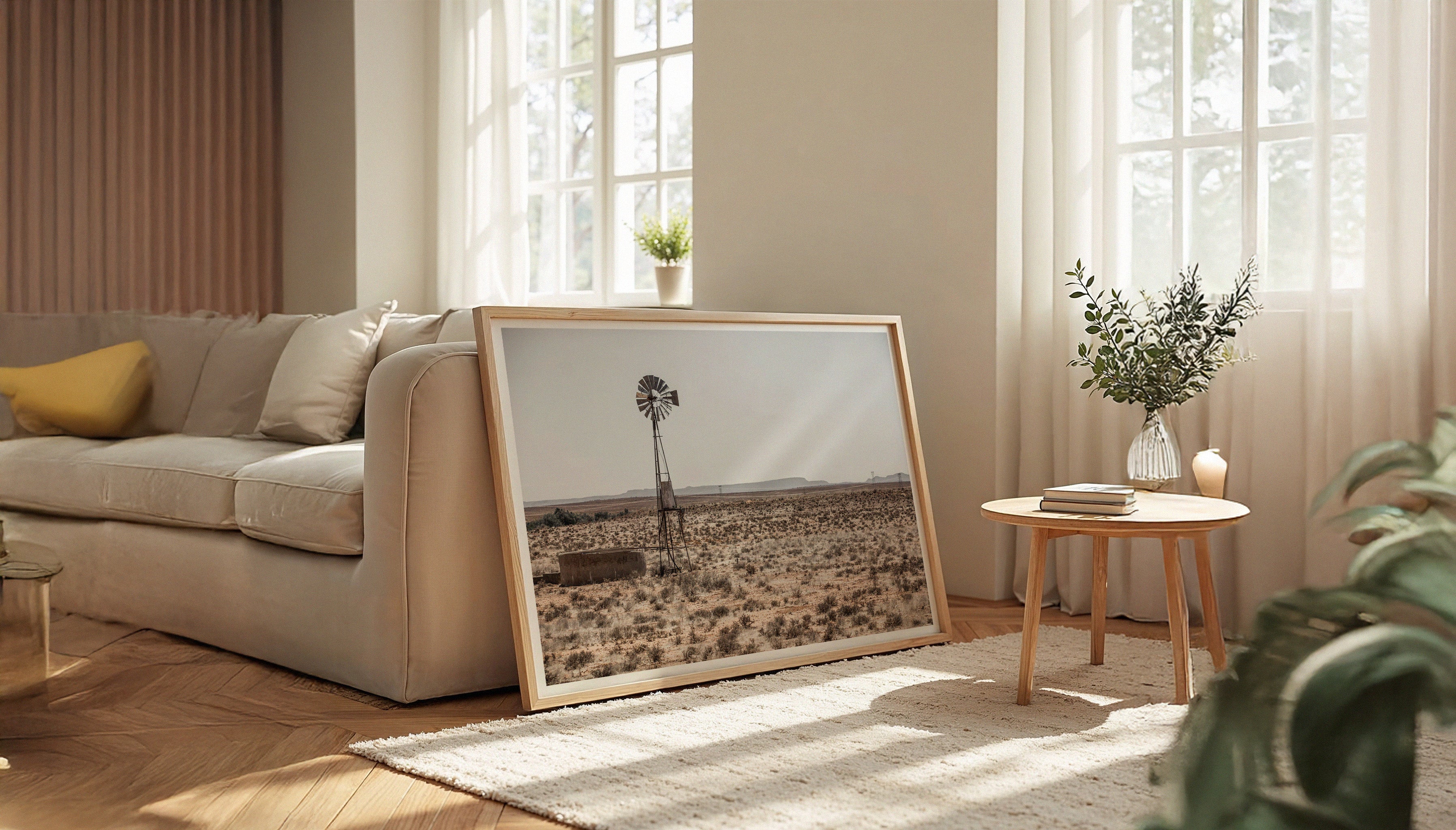 An African-inspired fine art print by Charles Johnstone shown in a wooden frame leaning against a sofa in a modern living room.