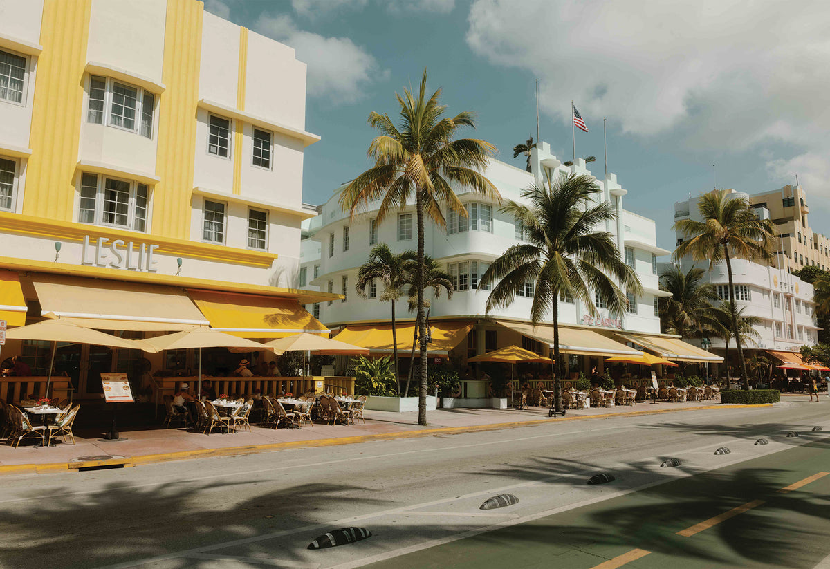 A photograph by Hannes Kläger taken while exploring the Art Deco District in Miami, where palm tree shadows dance across the pastel-coloured buildings that line the street. A piece of wall art showing Miami's authentic vintage charm, available to buy on The Lost Works.