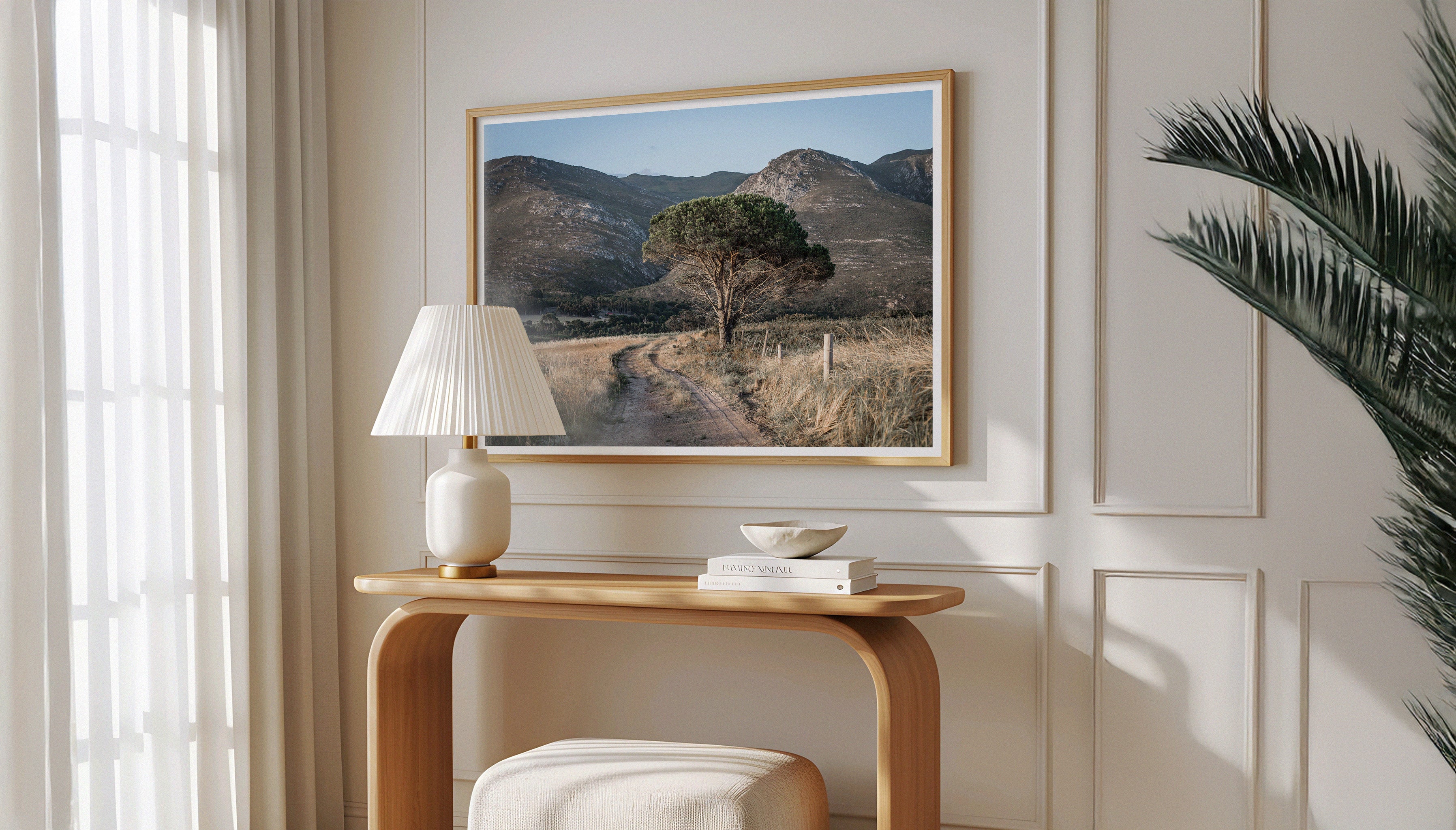Modern, Scandi interior with a wooden console table and Charles Johnstone's framed landscape print LONE TREE ON A TRACK hangs on a wall in a wooden frame.