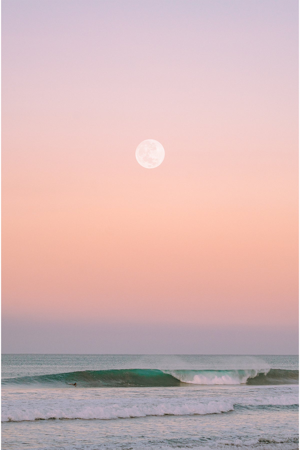 A full moon at sunrise over the ocean in Muizenburg, South Africa, with hues of pinks, oranges, blues and purples - a serene photography print by Evie Johnstone.