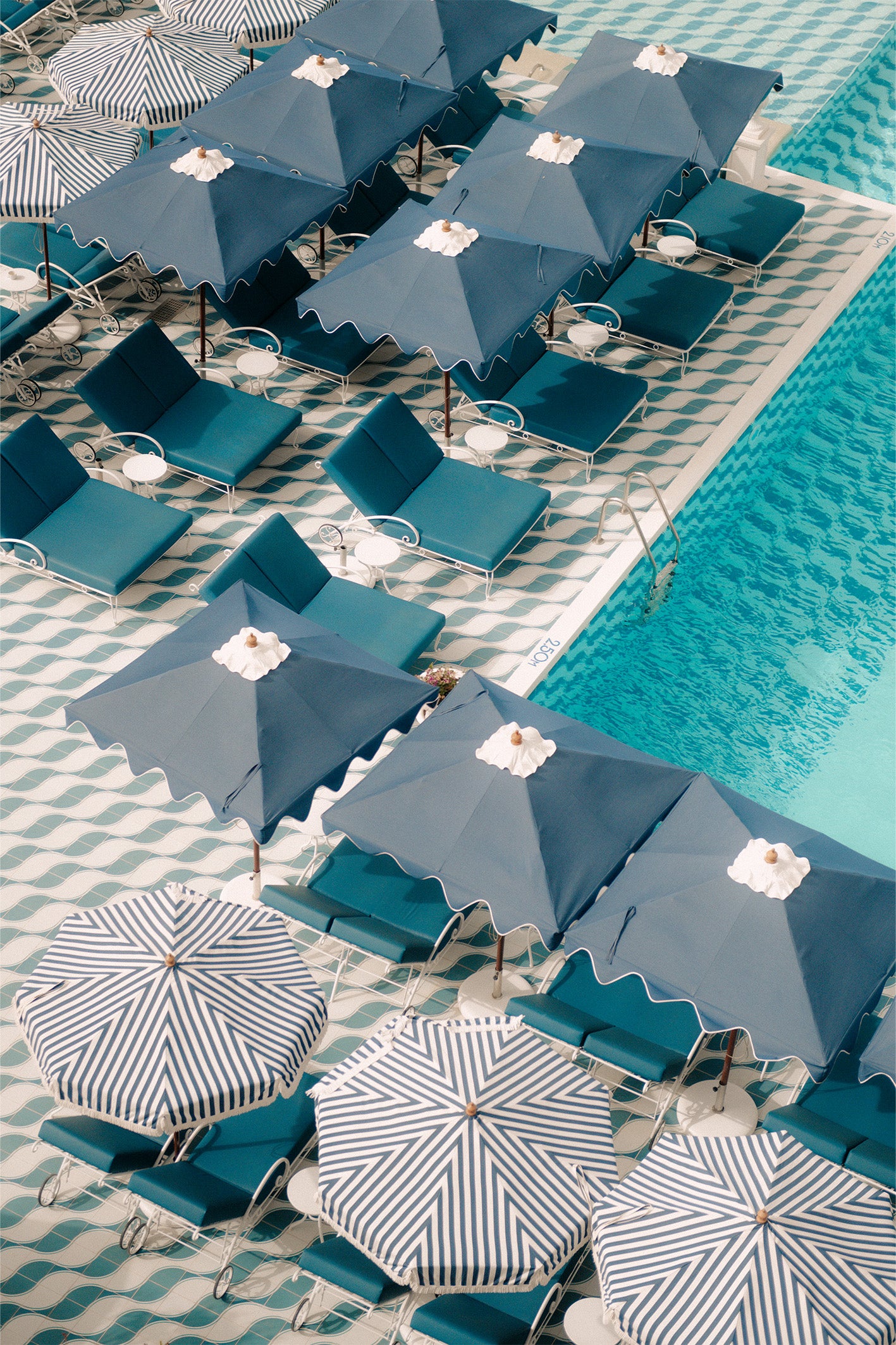 The pool at Ibiza's Mongibello Hotel shot from above, showing it's playful design patterns in bold blues and teals, a fine art print by Evie Johnstone.