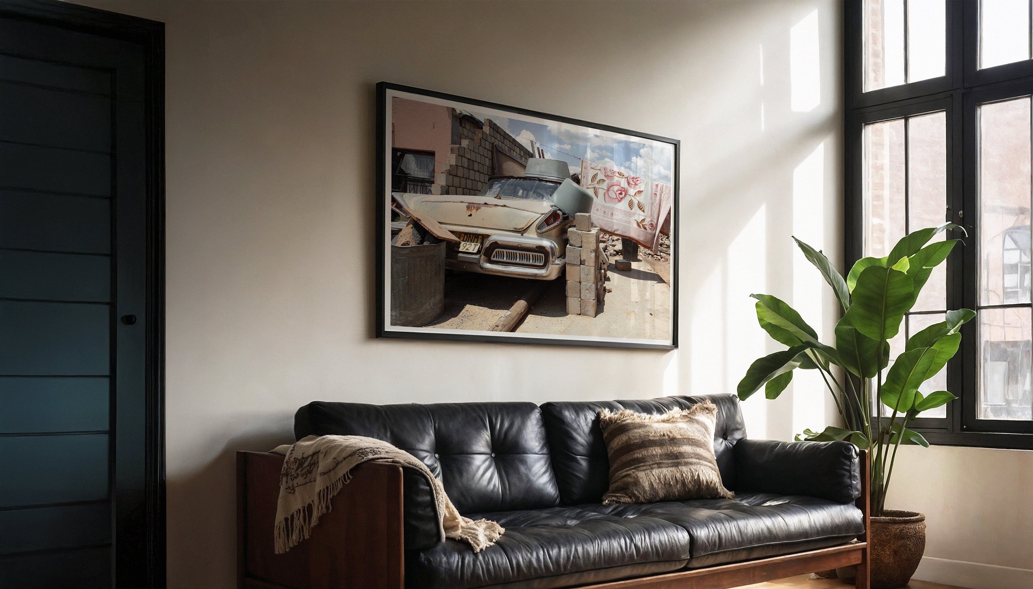 Charles Johnstone's PRIDE & JOY fine art photography print hanging in a black frame with a white border in a modern living room with a black leather sofa and plants.