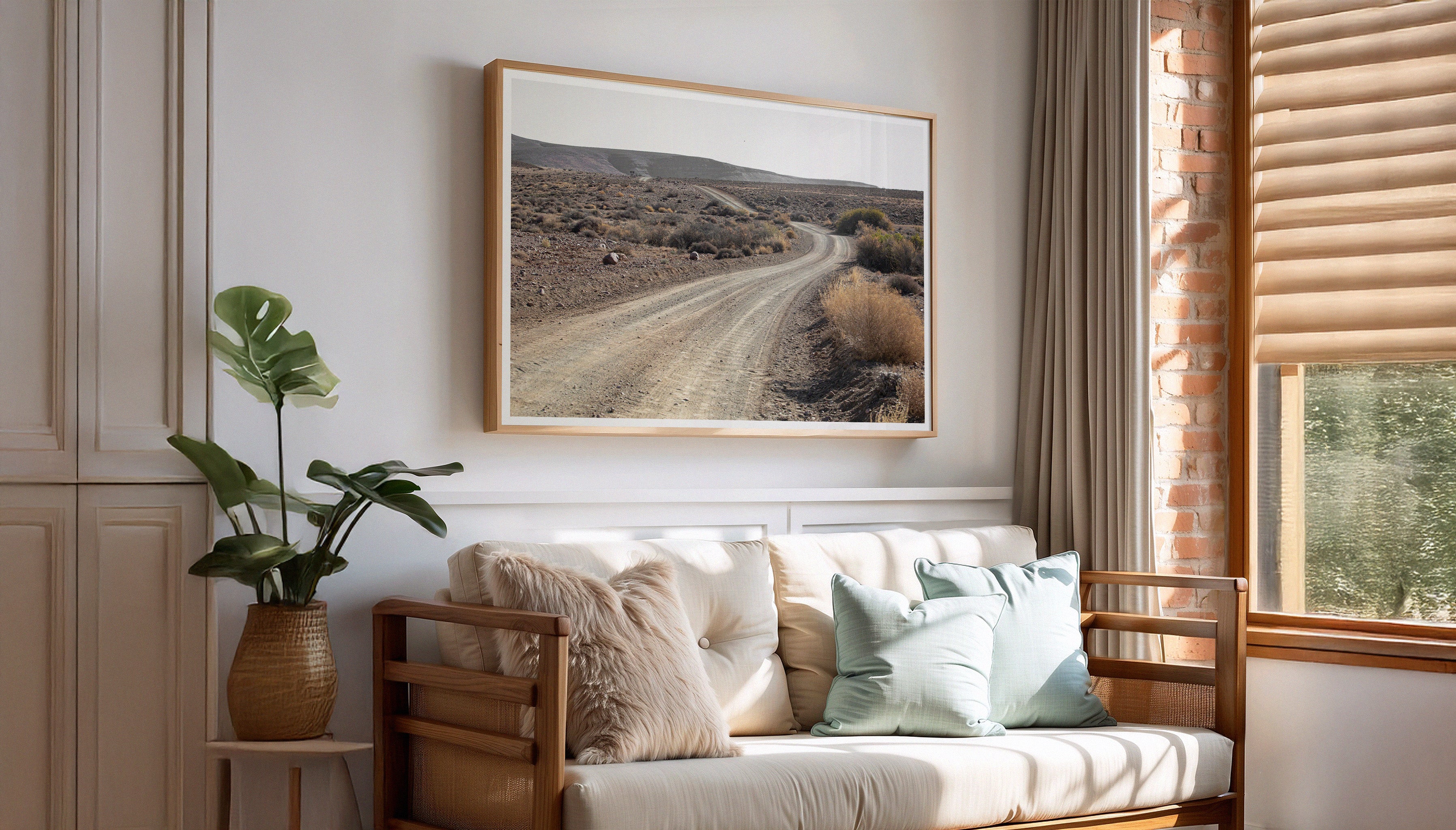 Charles Johnstone's 'Road To Nowhere' in a wooden frame above a sofa in a natural, neutral living room setting.