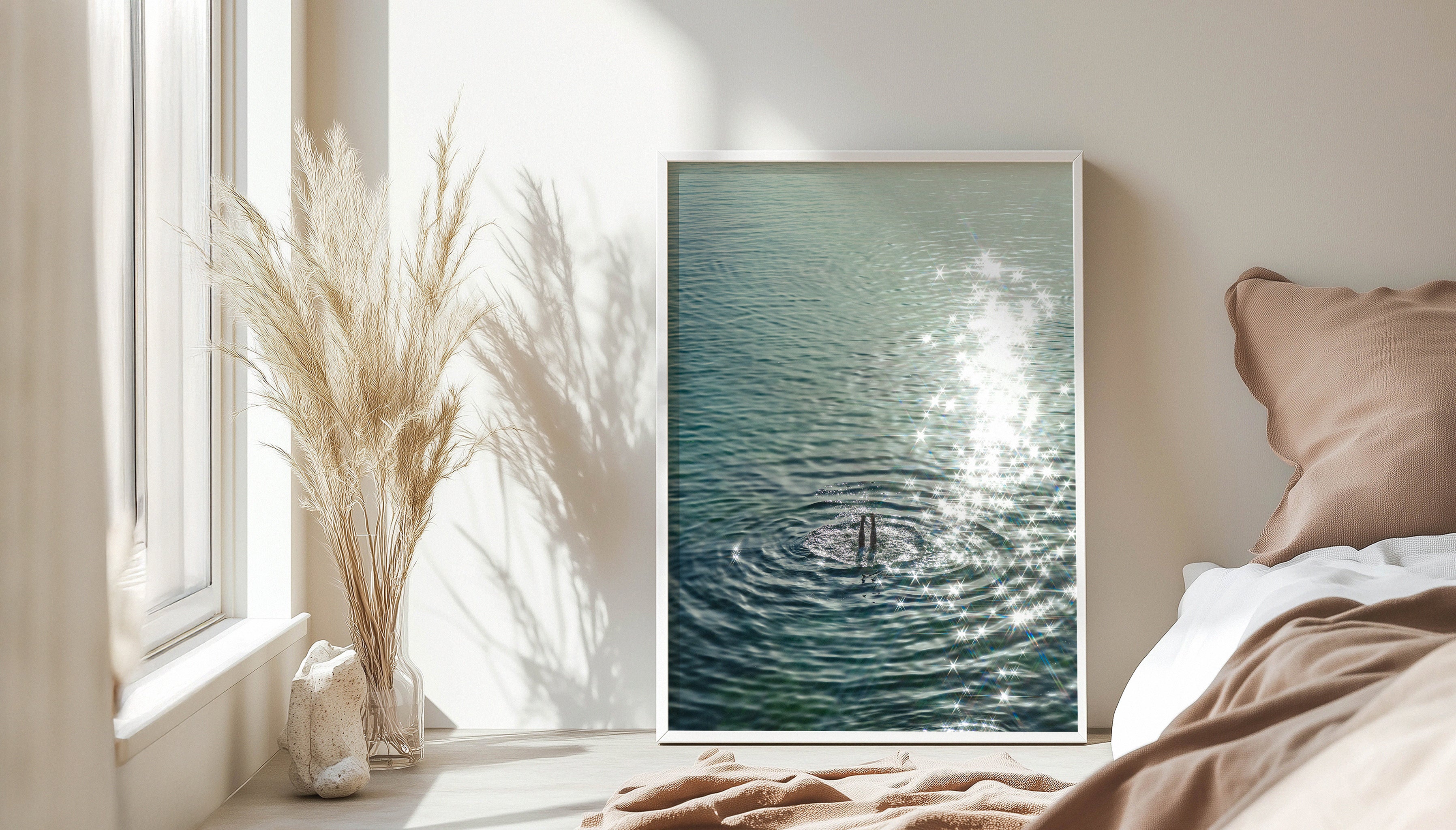 A wide view of a pink and white bedroom with pampas grass, and SEA LEGS by Evie Johnstone leaning against a wall in a large white frame.