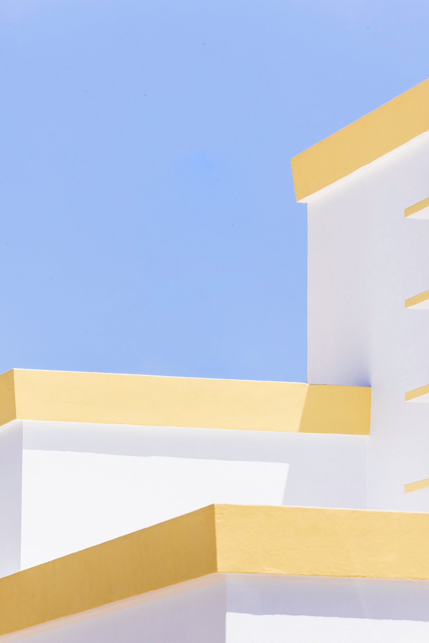 A bright white block with yellow accents against the Algarve's typical blue sky instills that glorious summer feeling. Fine art print by Will Bremridge, available to purchase on The Lost Works with a free framing service.