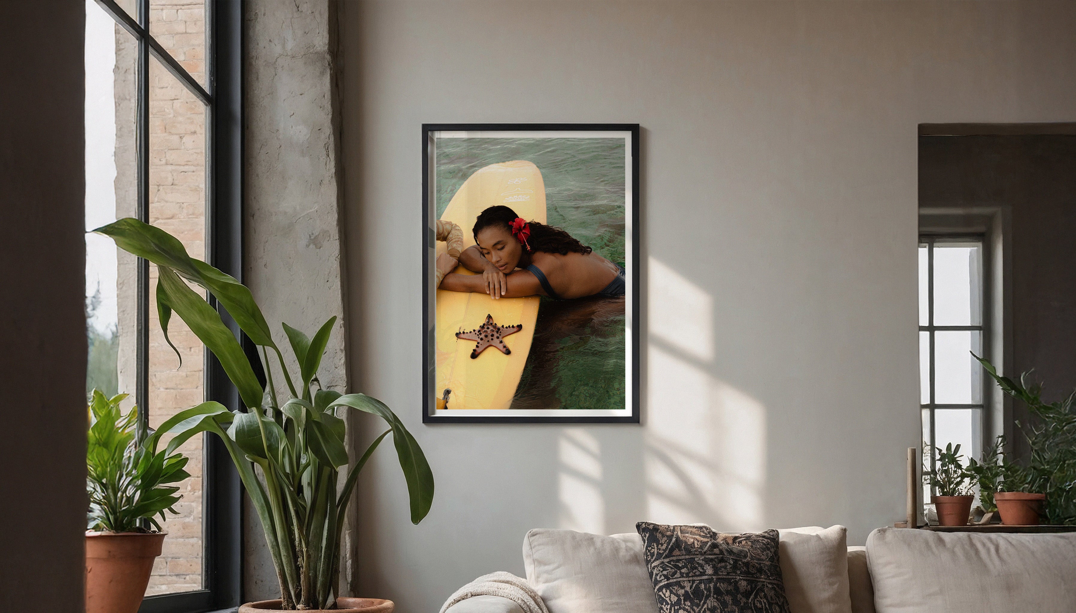 Evie Johnstone's STARFISH fine art photography print hanging on a muted grey wall in a large black frame in a living room setting with big plants and a grey sofa.