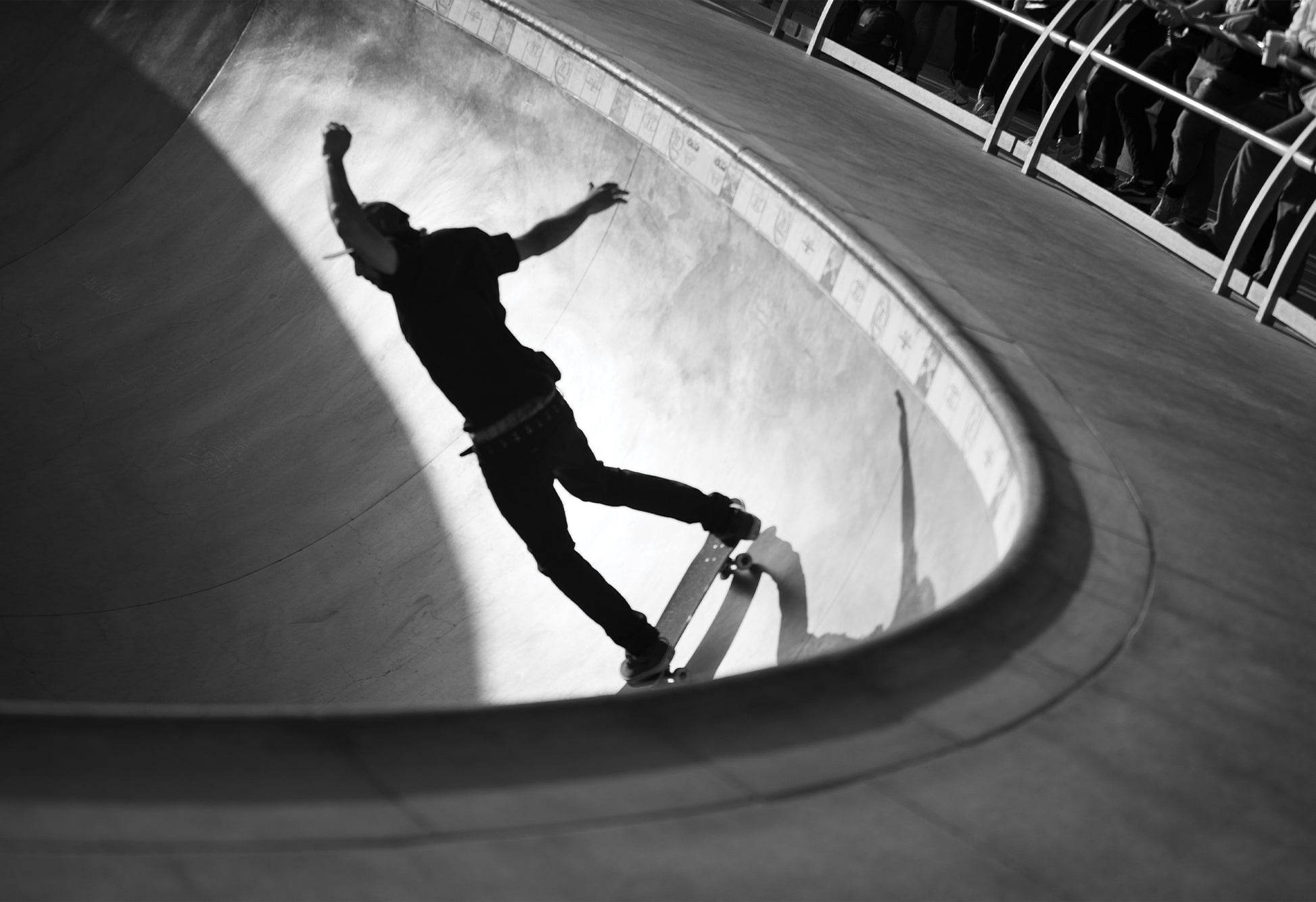 Black and white photography print of a skateboarder riding a curve at Venice Skatepark, arms raised mid-motion in a dramatic play of light and shadow.