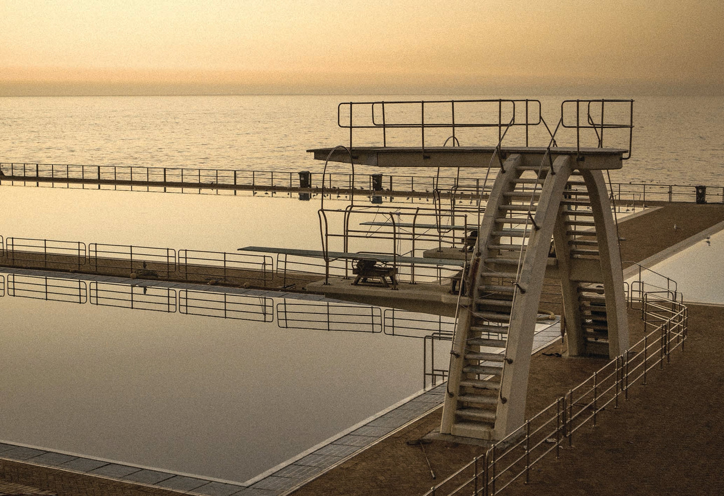 The high diving board at Sea Point Pavillion shot at late sunset by Charles Johnstone. A fine art photography print available to purchase at The Lost Works as a ready-to-hang framed piece of wall art.