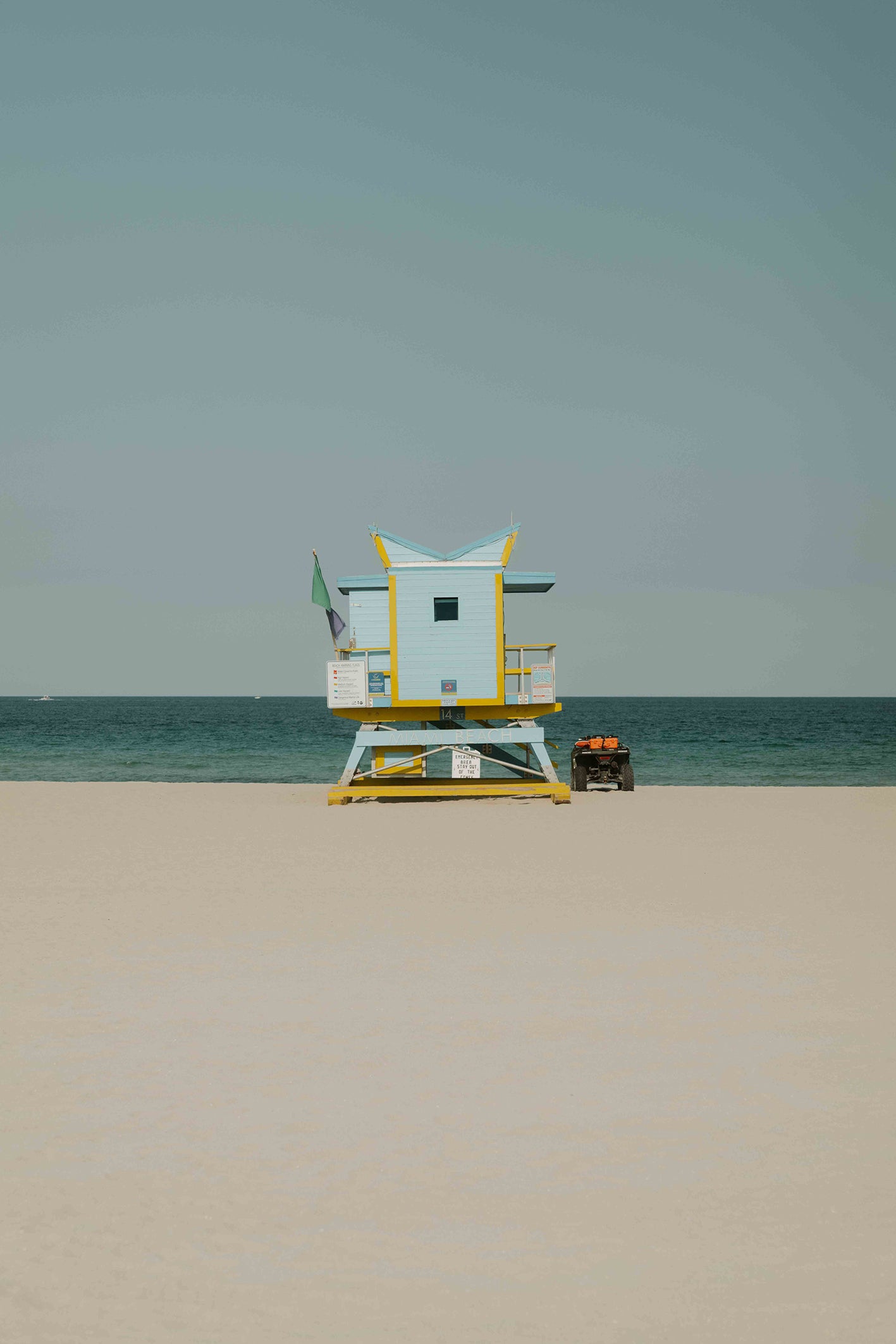 A fine art photography print by Hannes Klaeger, of one of the iconic lifeguard towers on Miami Beach, USA. This particular tower found at 14th St has an abstract roofline paired with a soft pastel blue, accented with yellow - framed perfectly by the sand, sea and sky.