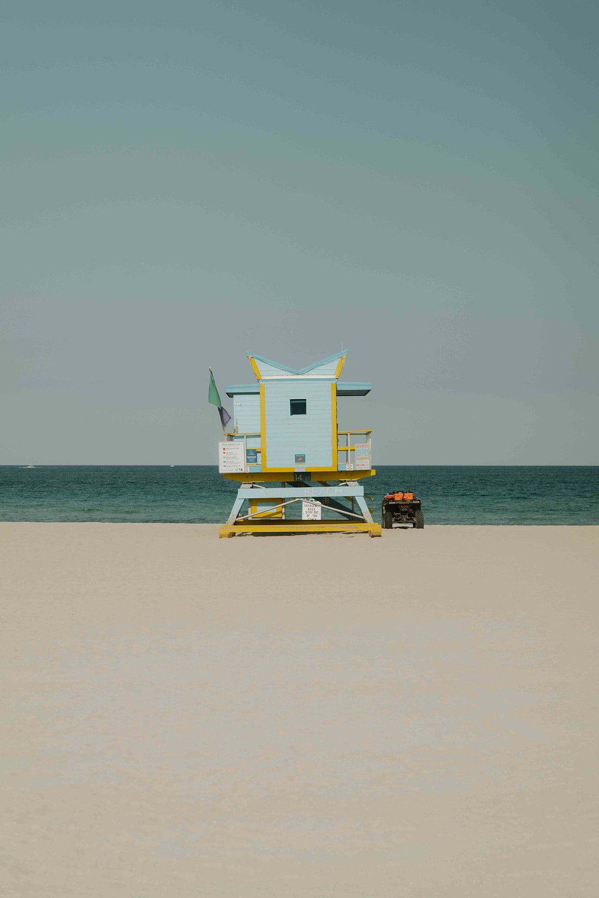 A fine art photography print by Hannes Klaeger, of one of the iconic lifeguard towers on Miami Beach, USA. This particular tower found at 14th St has an abstract roofline paired with a soft pastel blue, accented with yellow - framed perfectly by the sand, sea and sky.