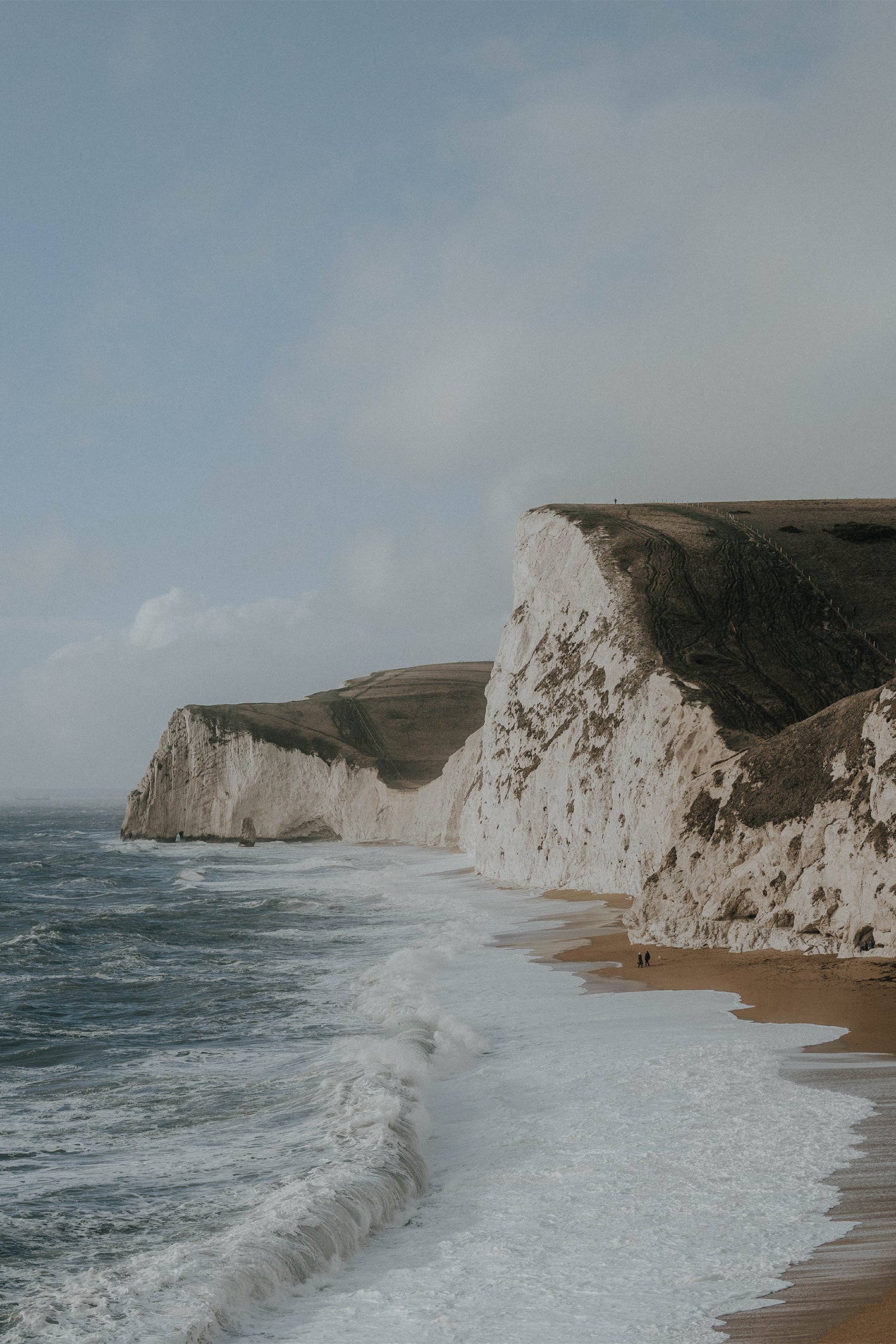 Dramatic sea cliffs and wild coastline along England’s Jurassic Coast under blue skies – a fine art travel photograph by Sam Morris.